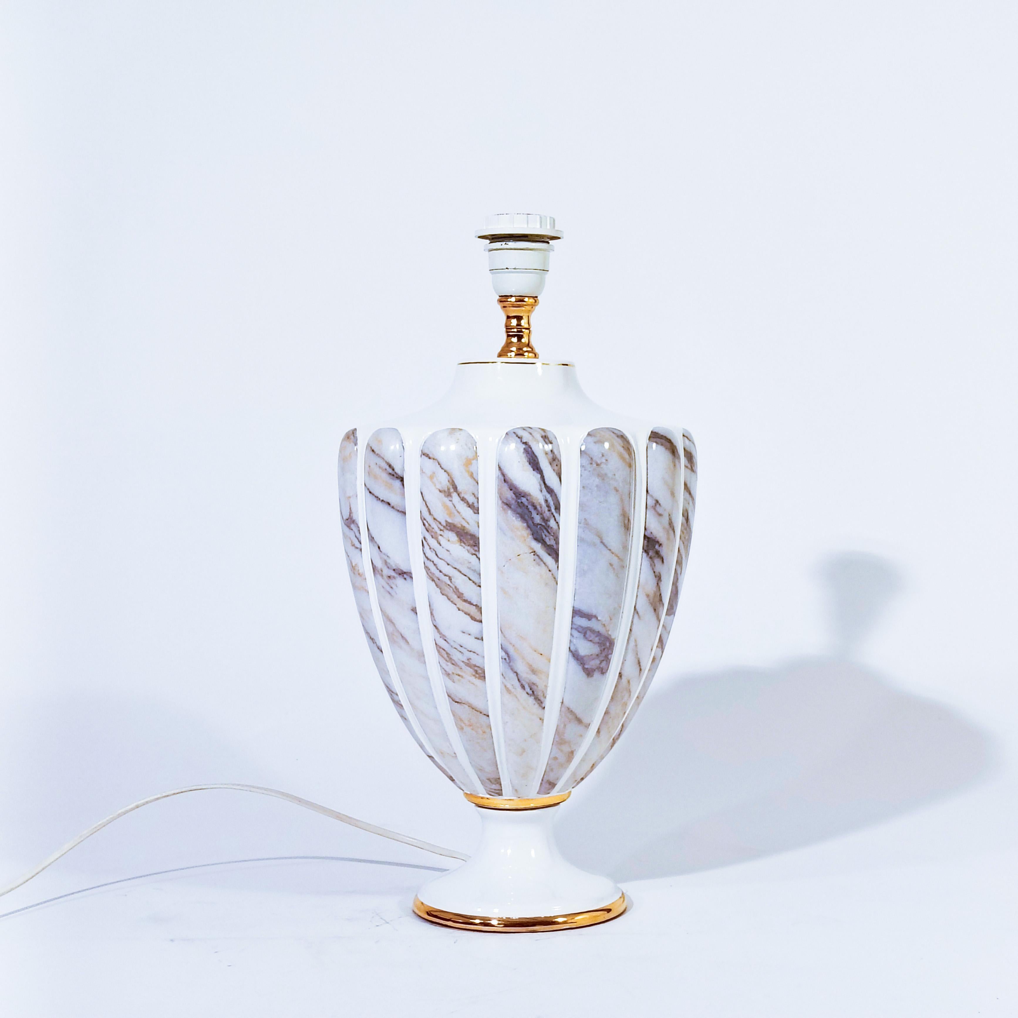 Lampada da tavolo in stile Hollywood Regency e Neoclassico, anni '80. Realizzato in ceramica bianca con rilievi effetto marmo molto realistici e dettagli dorati. Struttura in ottone dorato cromato. Stile rococò, classico e postmoderno.
Per una