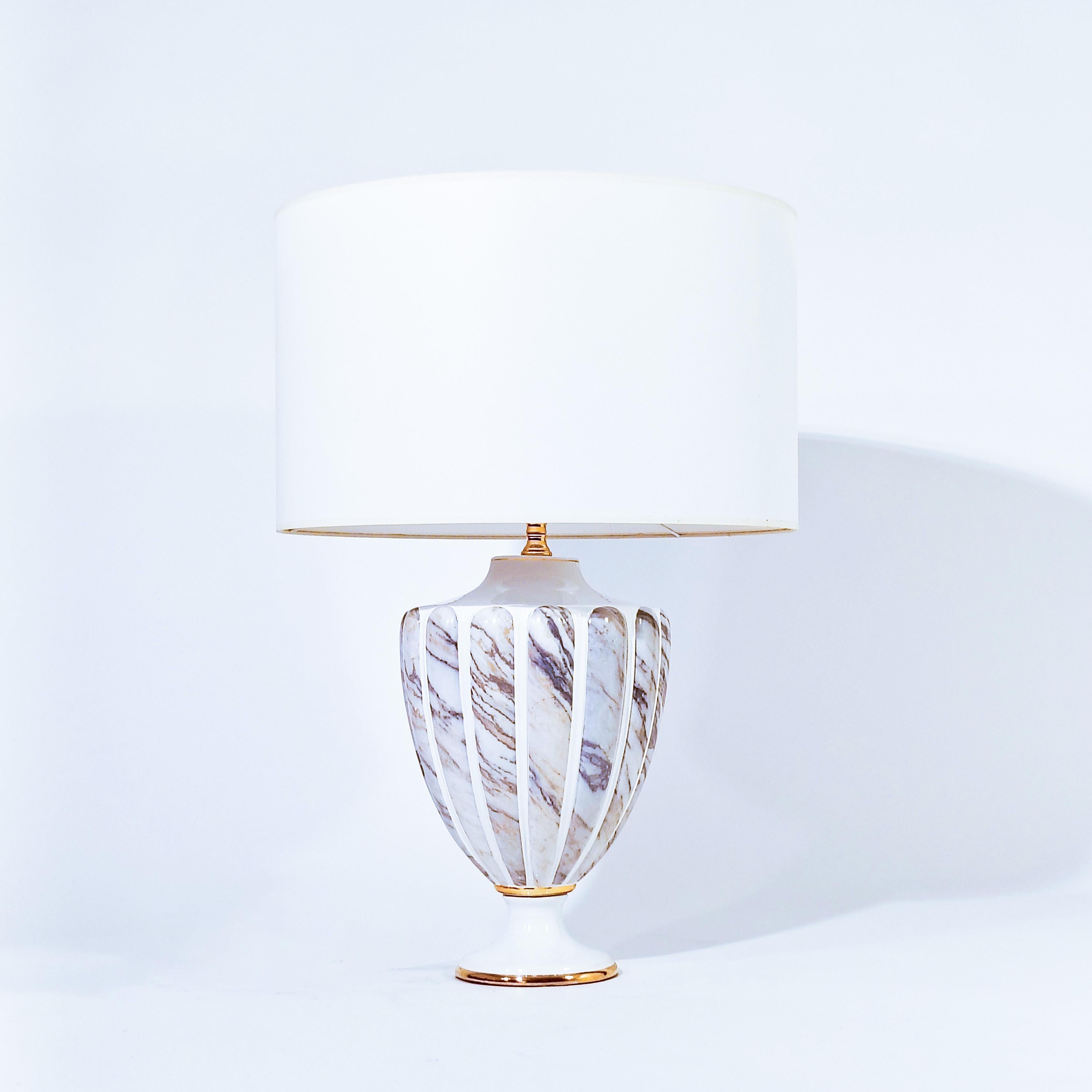 Tischlampe im Stil des Hollywood Regency und des Neoklassizismus, 1980er Jahre. Aus weißer Keramik mit sehr realistischen Reliefs in Marmoroptik und vergoldeten Details. Verchromte Struktur aus goldenem Messing. Rokoko, klassischer und postmoderner