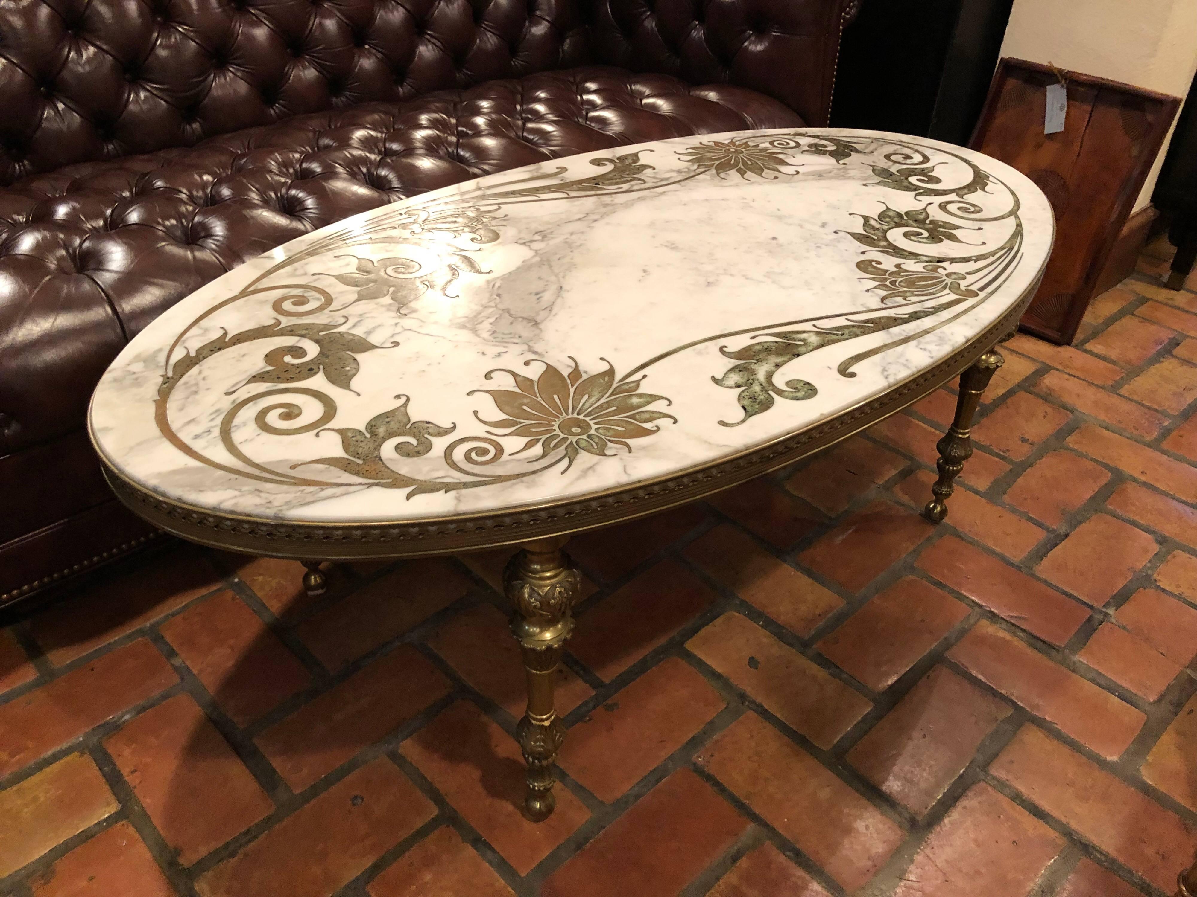 Hollywood Regency marble-top coffee table with inlay. Elegant and special this oval table will complement any living room space. Brass turned legs with a fitted and enclosed brass gallery for the marble top. Gorgeous designed inlay to marble top.