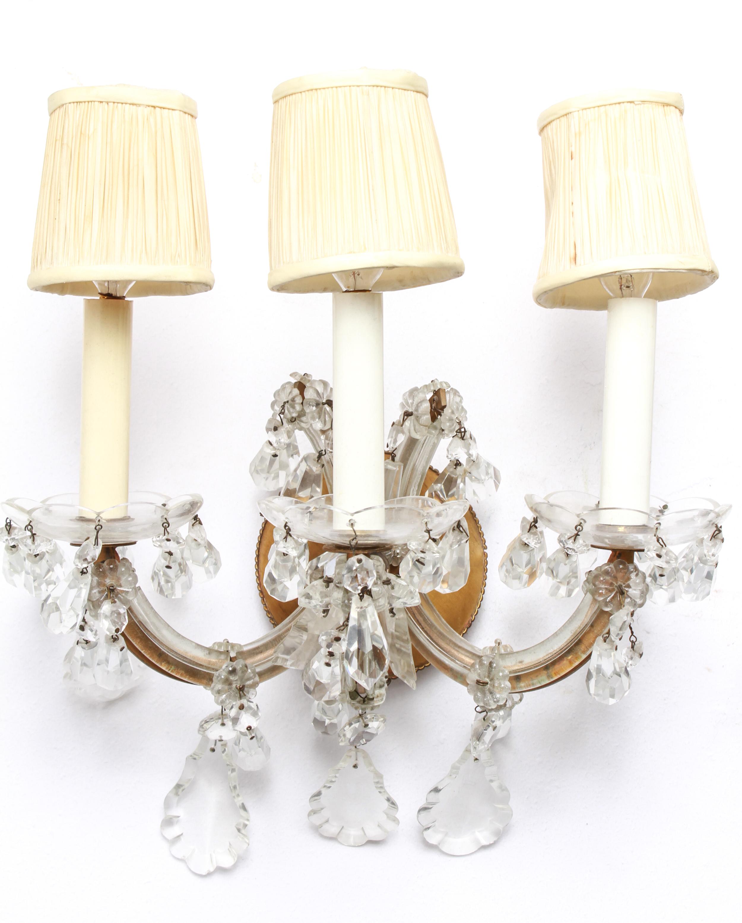 Hollywood Regency pair of Maria Theresa wall sconces in brass with glass pendants and diminutive shades. The pair was made around the mid-20th century and is in great vintage condition with age-appropriate wear.