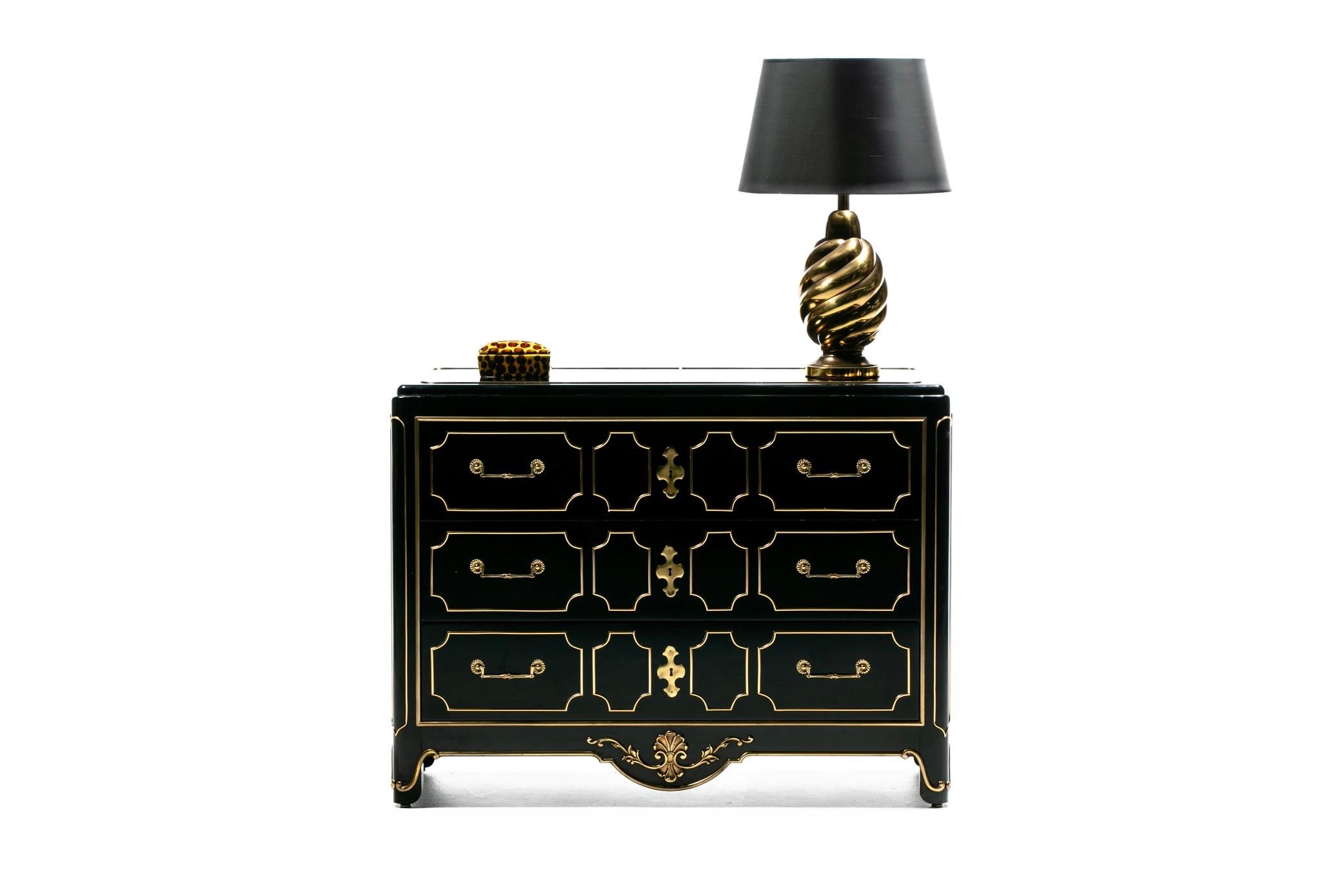 A première vue, cette commode Mastercraft des années 1970 va immédiatement attirer votre attention. Beaucoup de détails pour le plaisir des yeux. Les accents et la quincaillerie en laiton patiné doré brillent sur sa finition laquée noire. Les