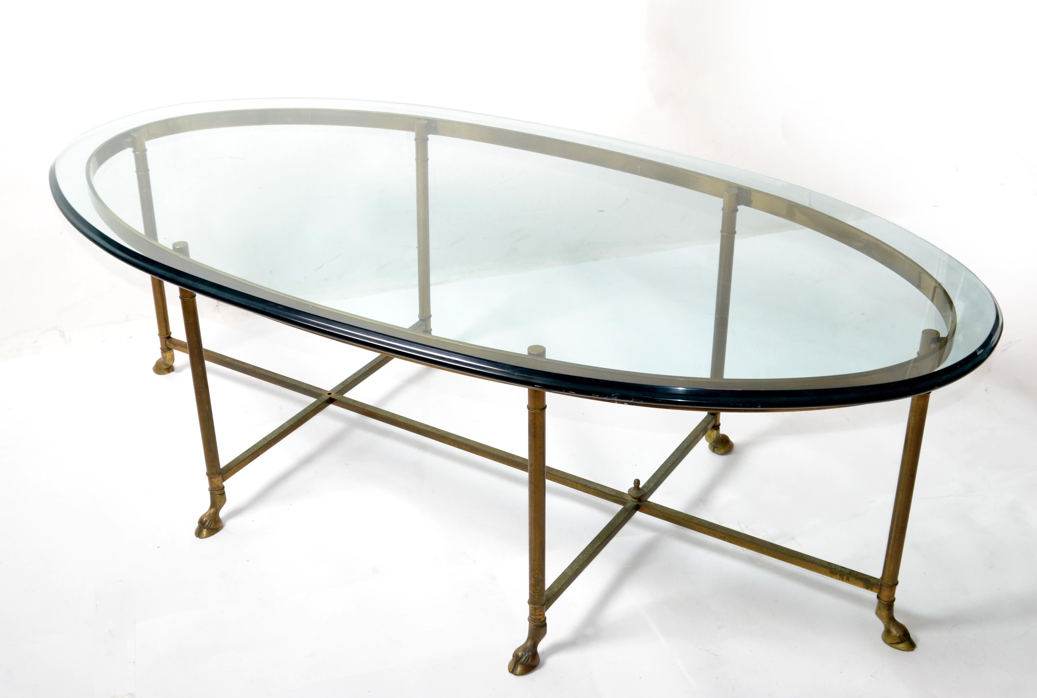Hollywood Regency Mastercraft brass coffee table with hoof feed & thick classical racetrack glass top.
The base shows a well-aged patina, and the oval heavy glass top is beveled.
This table is craftsmanship pure and is a great addition to any