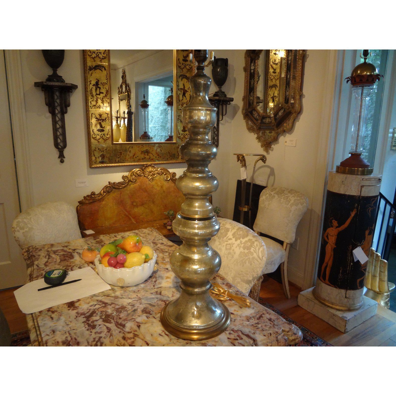 A glamorous circa 1960 Hollywood Regency mercury glass table lamp on a gilt base. The lamp is newly wired with new fittings. This tall lamp is silverish in color.