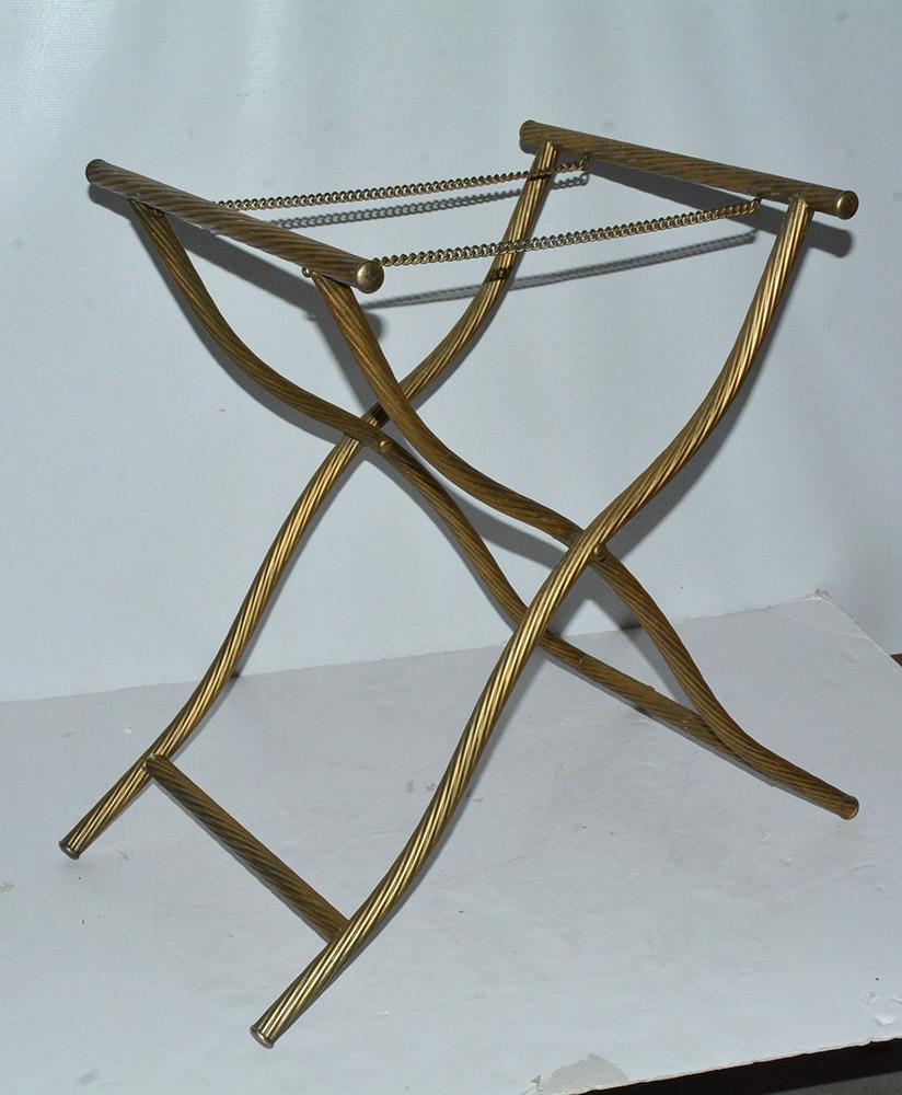 The vintage gold gilt stylish and elegant Hollywood Regency style luggage rack is made of undulating metal piping with a spiral rope-like finish. Two chains hold the rack in place when open and is also collapsible for storage. Better looking and