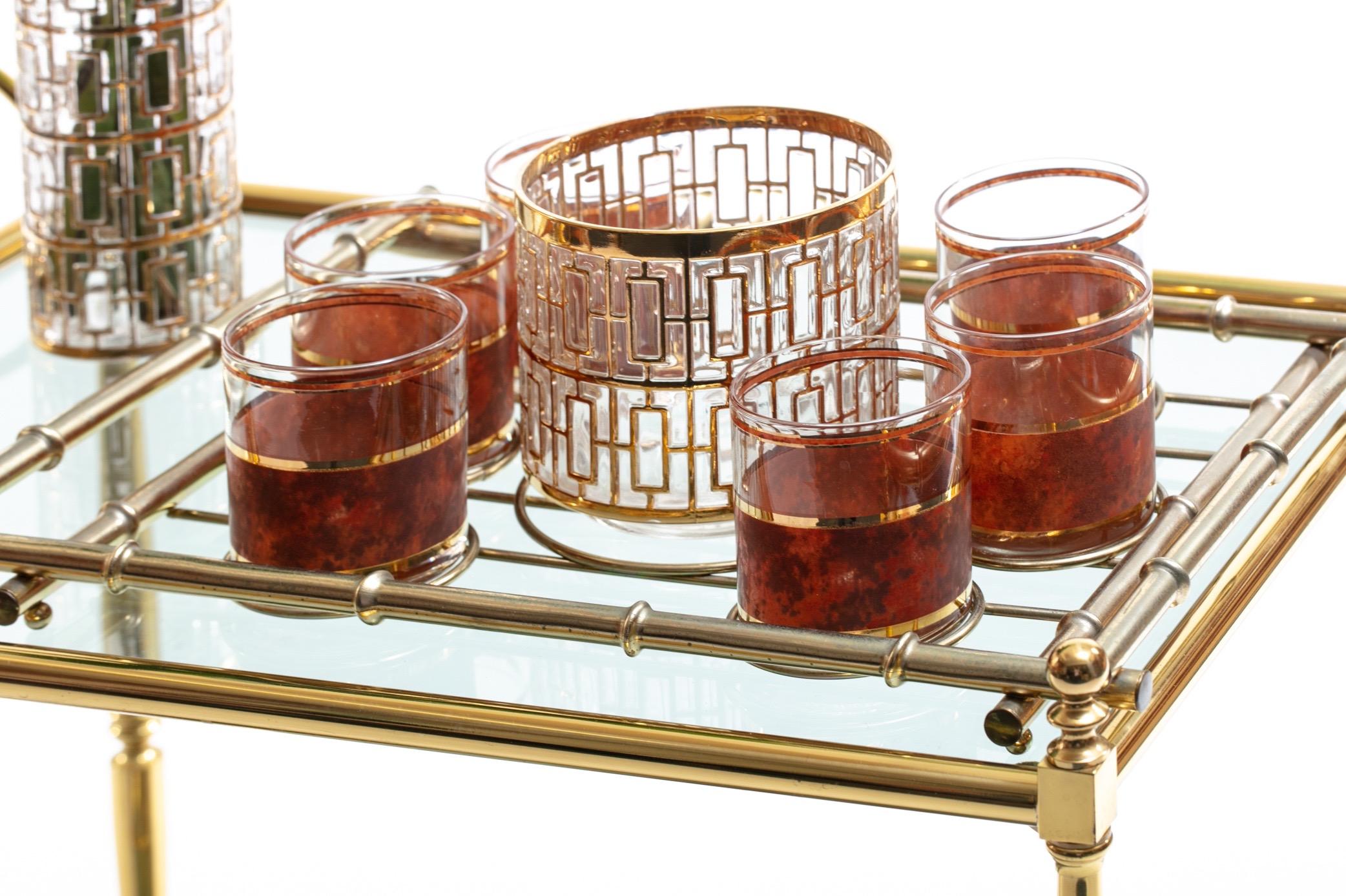 Beautiful and elegant mixed Hollywood Regency Mid-Century Modern barware set featuring 22-karat gold hand painted ice bucket by Imperial Glass in the famed Shoji pattern, six rocks glasses with 22-karat gold plated detail and faux suede finish, and