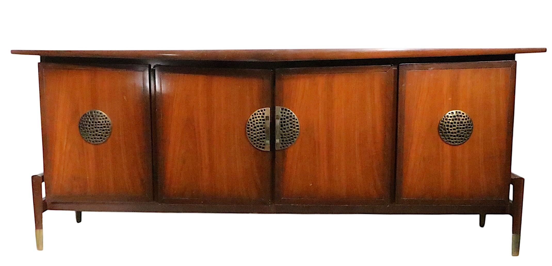 Impressionante comò in stile Mid Century, Hollywood Regency, Asia Modern, disegnato da Helen Hobey Baker. Il comò è caratterizzato da un piano sporgente stilizzato, sopra una cassa con  quattro ante che si aprono per rivelare i cassetti interni. Le