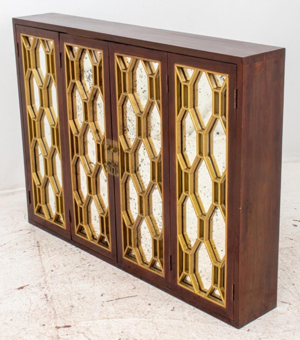 Hollywood Regency midcentury style hanging wall cabinet, the custom made hardwood case with four-panel folding cabinet doors, each with gilded lattice mullions over antiqued mercury mirror, opening to reveal an interior ideal for hiding a television