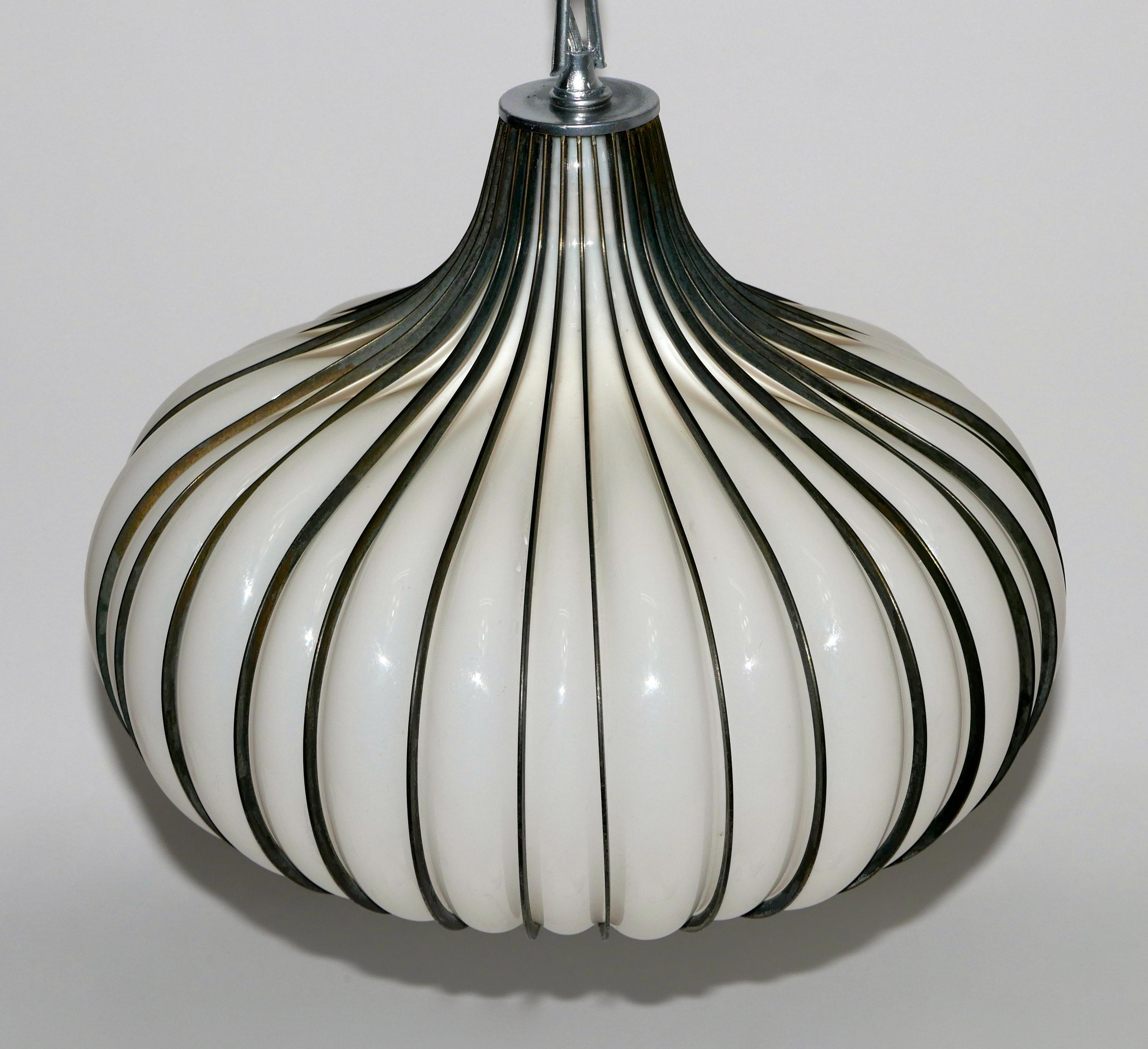 A Hollywood Regency / California modern hanging pendant. Hand blown onion form white glass with a ribbed brass plated steel frame, long swag chain and canopy. Chain measures 48 inches. Can be shortened if requested.

Midcentury
Lightcraft of