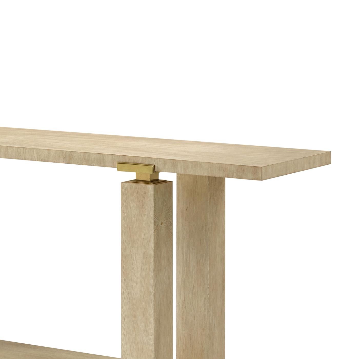 Minimalist Console in a light Martini finish exemplifies this ethos with sculptural clarity. Meticulously artisan made, its bold architectural frame features clean lines, block-style legs, and an open lower shelf for elegant display.

Polished brass