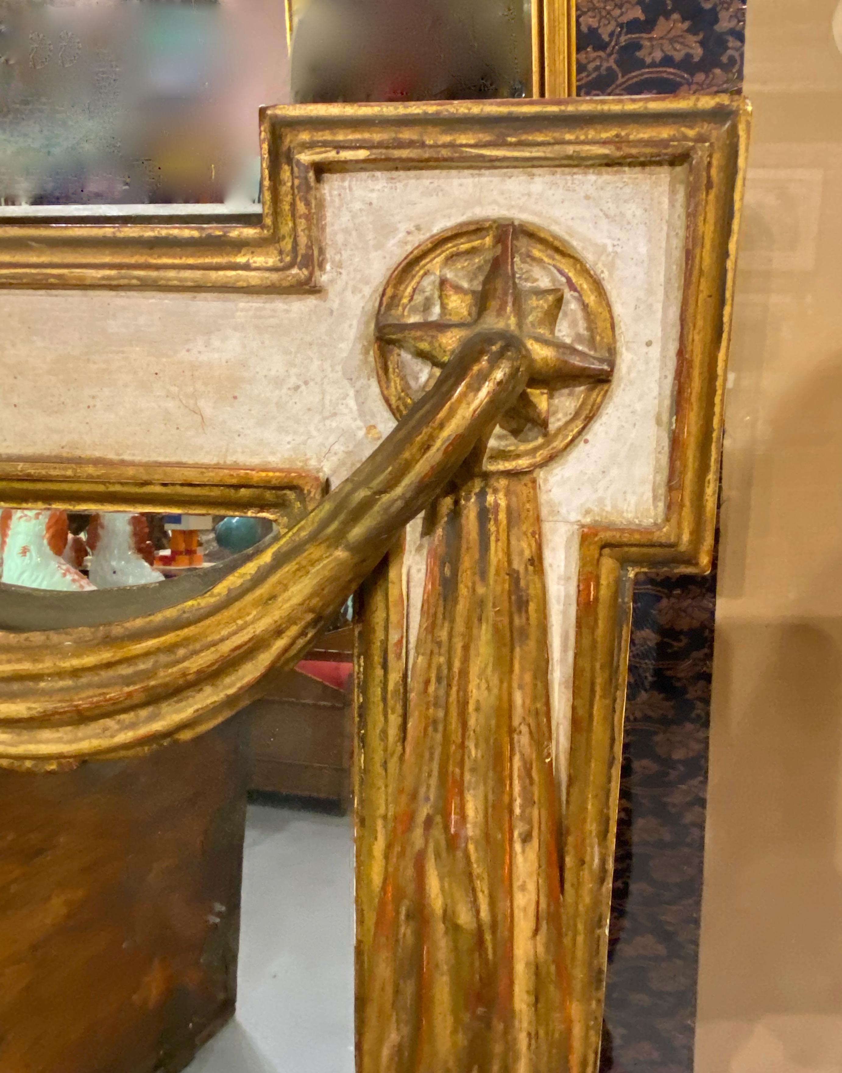 This is an impressive late 20th century mirror in the Venetian style. The mirror features a large carved and gold leafed center shell surrounded by neoclassical style drapery and gold leafed rosettes. All elements of the mirror are in very good