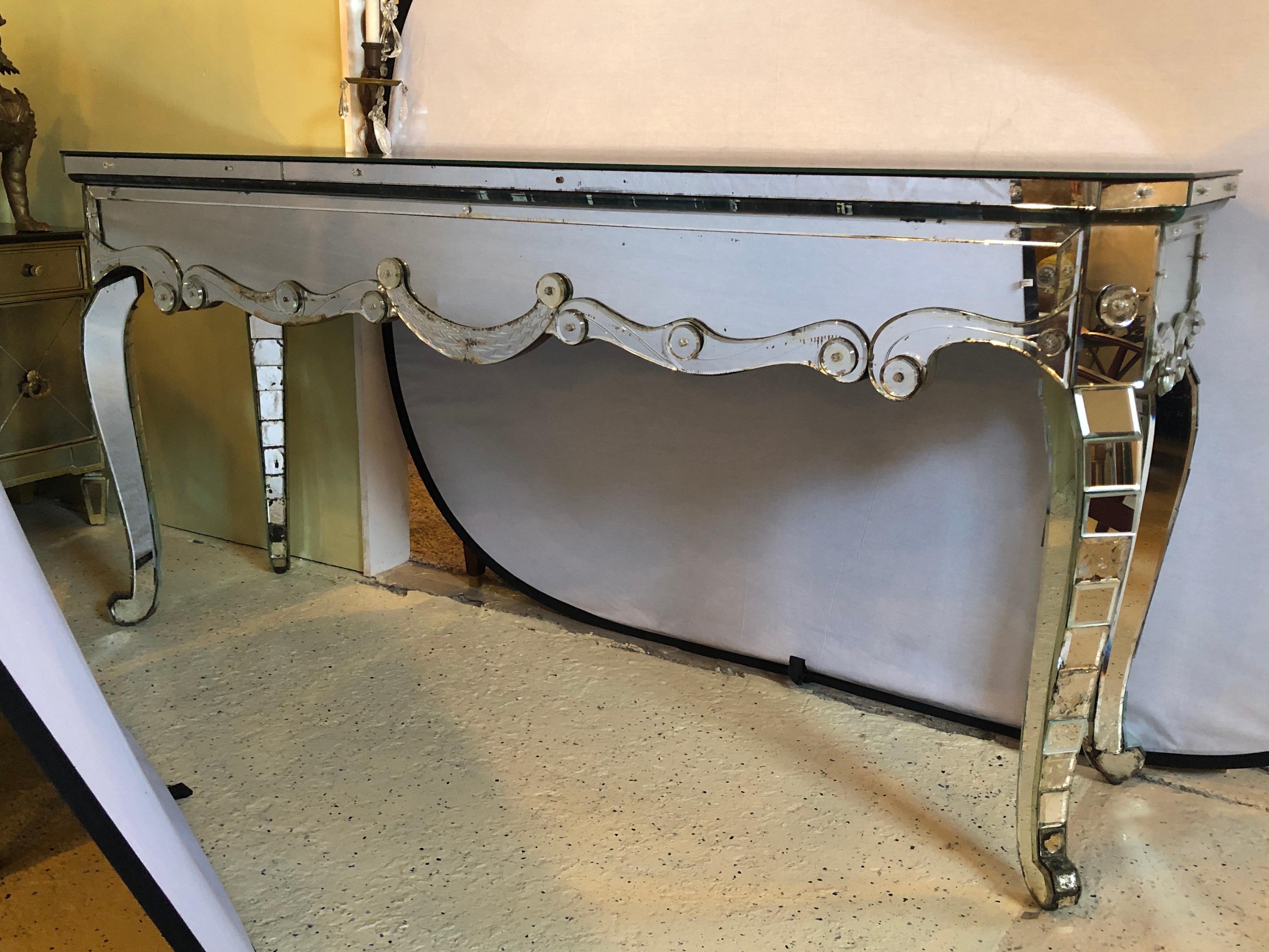 This one of a kind Hollywood Regency mirrored console with applied decoration and cabriolet legs is a must have in any home setting. Having a fish scale Decoration in an all-over beveled mirror design this seemingly spectacular console or sideboard