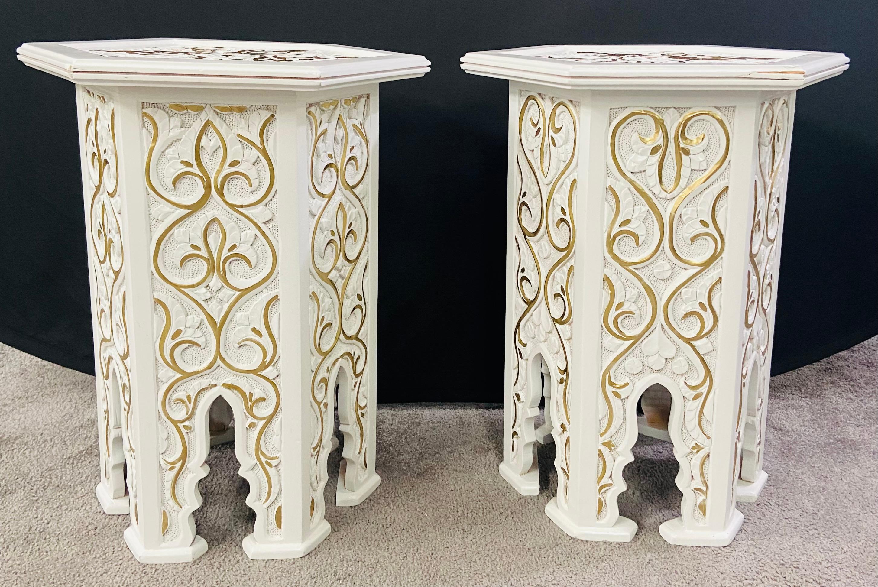 An exquisite pair of Hollywood Regency Moroccan style side or end table featuring an hexagonal shape. The handmade tables are finely painted in white and decorated in leaves Pattern painted in gold and beautiful arches, a staple of the moorish