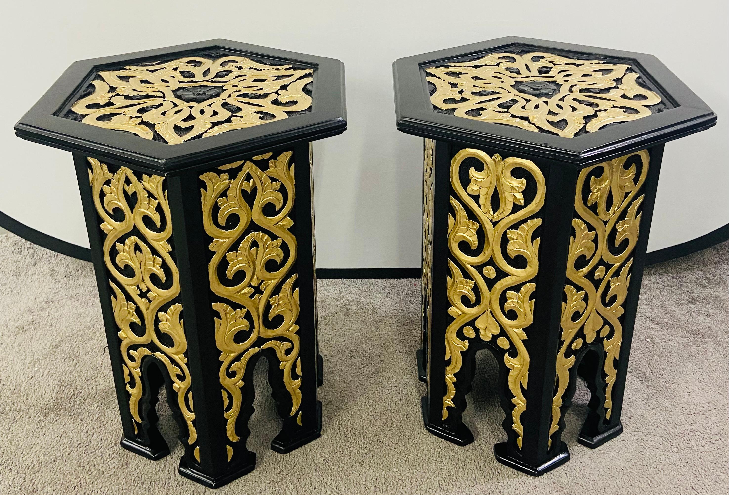 An exquisite pair of Hollywood Regency Moroccan style side or end table featuring an hexagonal shape. The handmade ebony tables are finely decorated in leaves Pattern painted in gold and beautiful arches, a staple of the moorish timeless