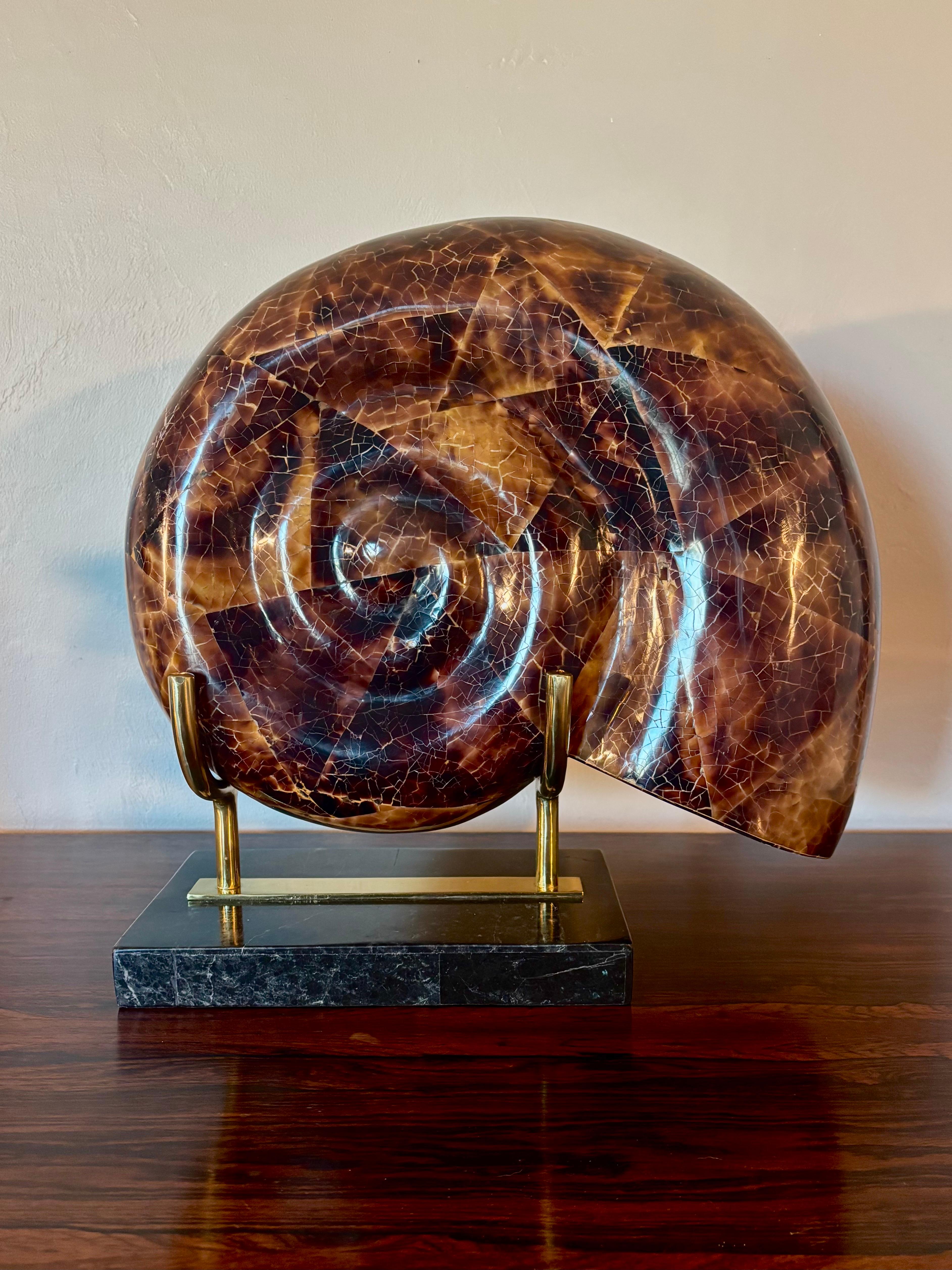 Stunning and large nautilus shell decor piece. Hollywood regency in style. Form is covered in coconut shell with a high gloss strong finish. Standing on a base of tessellated black marble and brass. 

Similar to decor pieces by the likes of Maitland