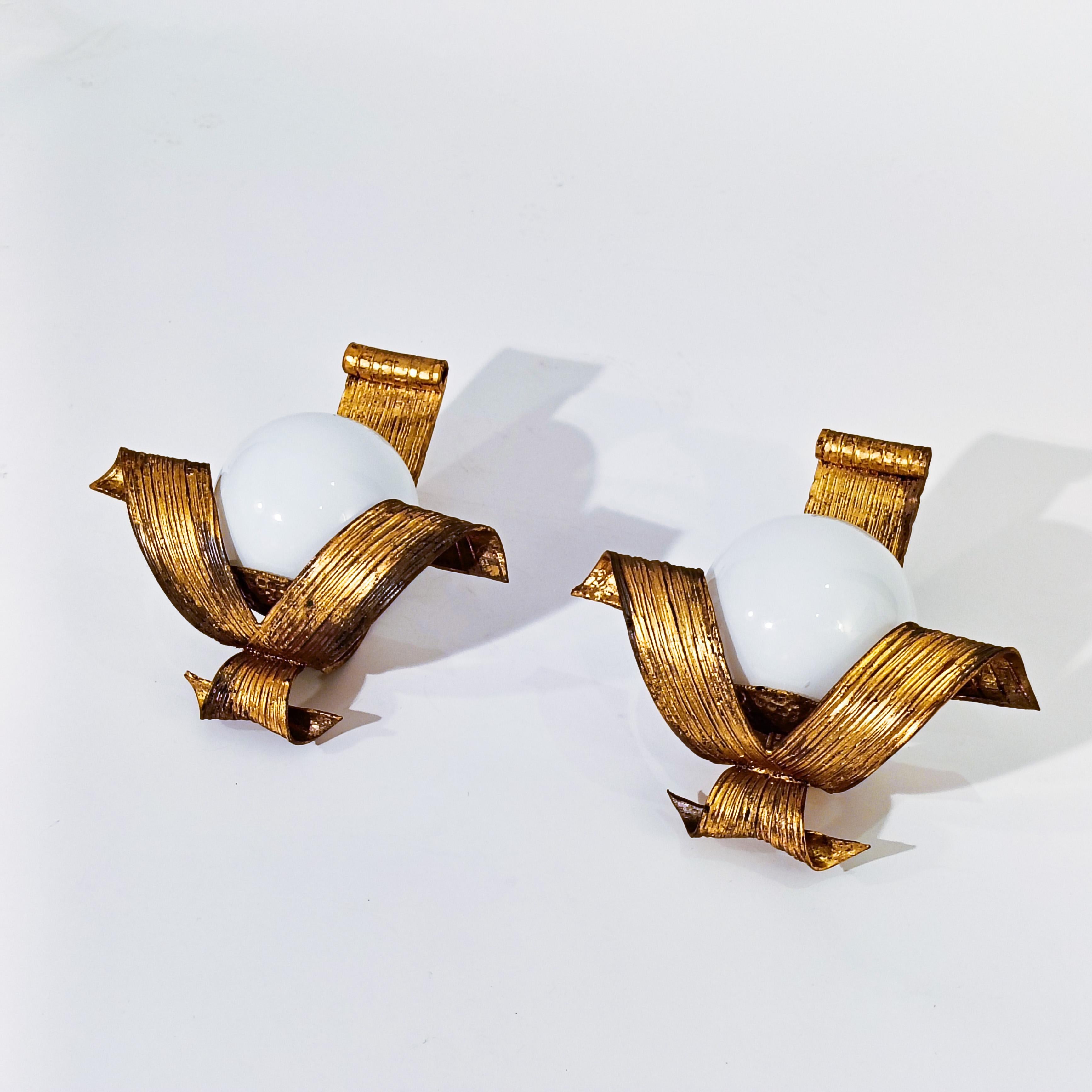 Hollywood Regency and Classic style gilded sconces by Ferro Art (also known as Ferroart), Spain, 1950s.
Handmade and hammered in solid wrought iron in the shape of a bow and gilded with gold leaf and gold paint. Opaline glass diffuser. Mid-Century