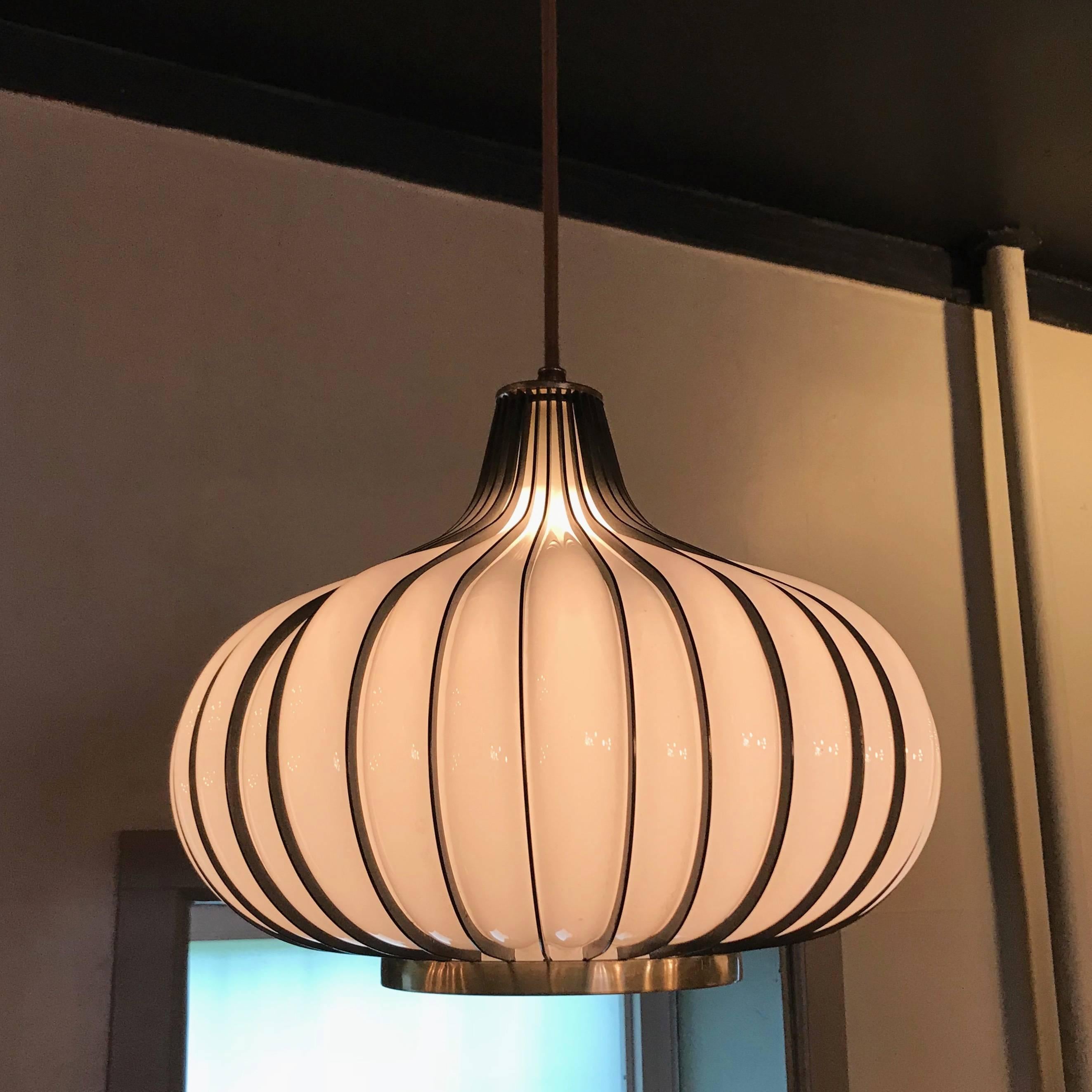 Midcentury, Hollywood Regency, garlic or onion shaped, swag, pendant light features blown milk glass shade encased in a brass-toned, steel frame. The pendant is newly wired with 6 feet of thick brown cloth cord.