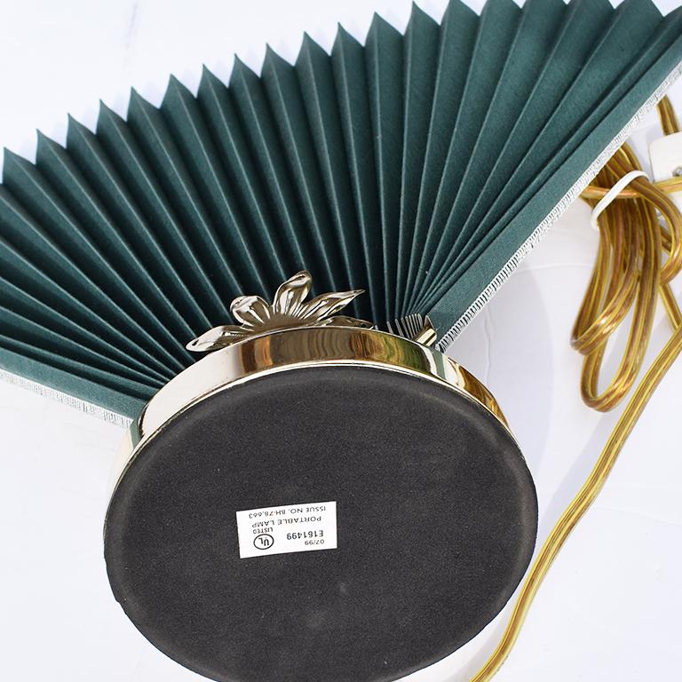Abstract, Mid-Century Modern, chinoiserie or Hollywood Regency style green accordion fan table lamp with gold floral motif at base. Reminiscent of Caprani style lighting, this beautiful deep green linen fan lamp is a statement piece that blurs the