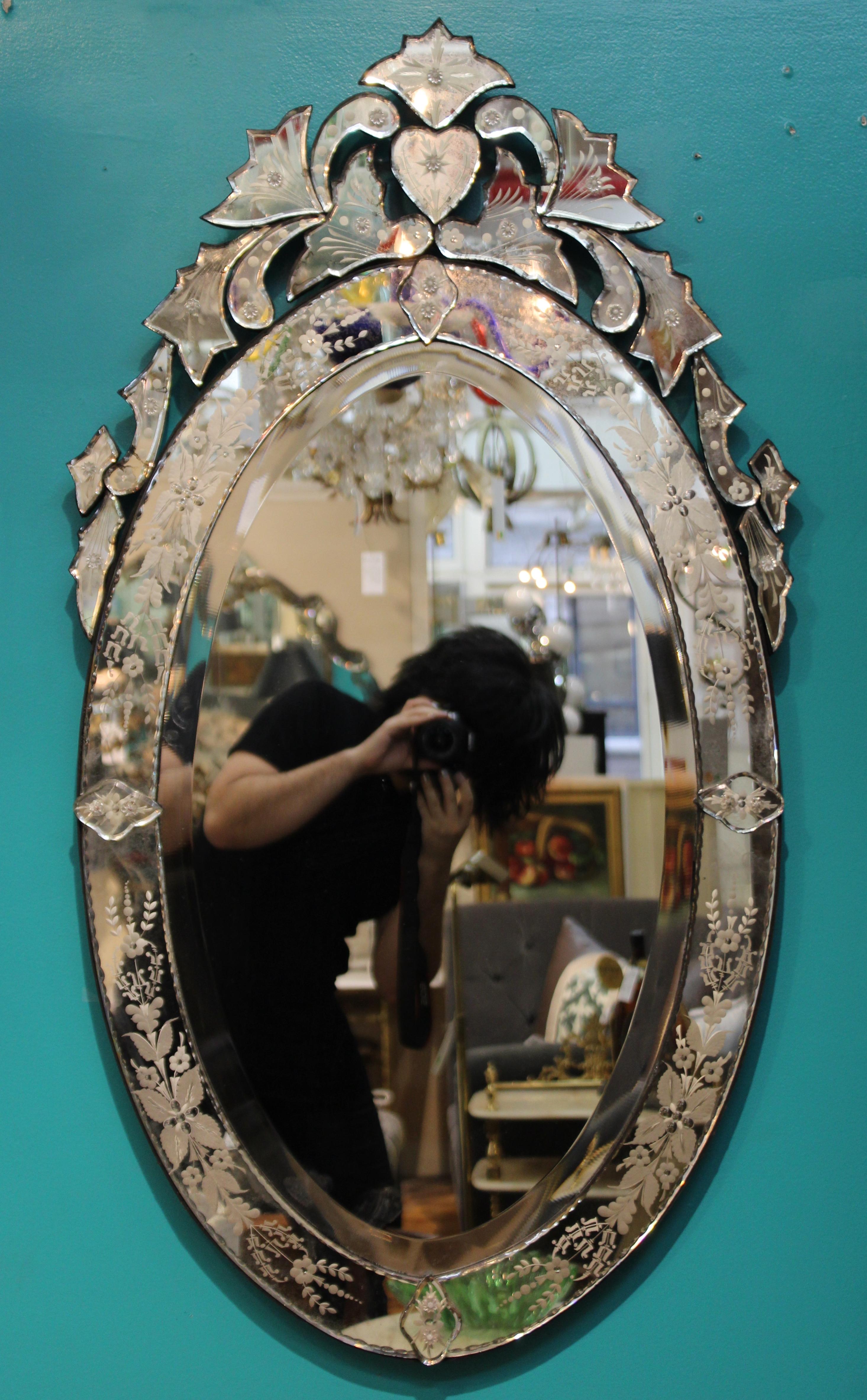 Hollywood Regency Venetian mirror in oval shape with decorative floral and foliate border. The piece was made in Italy in the 1940s and is in great vintage condition.