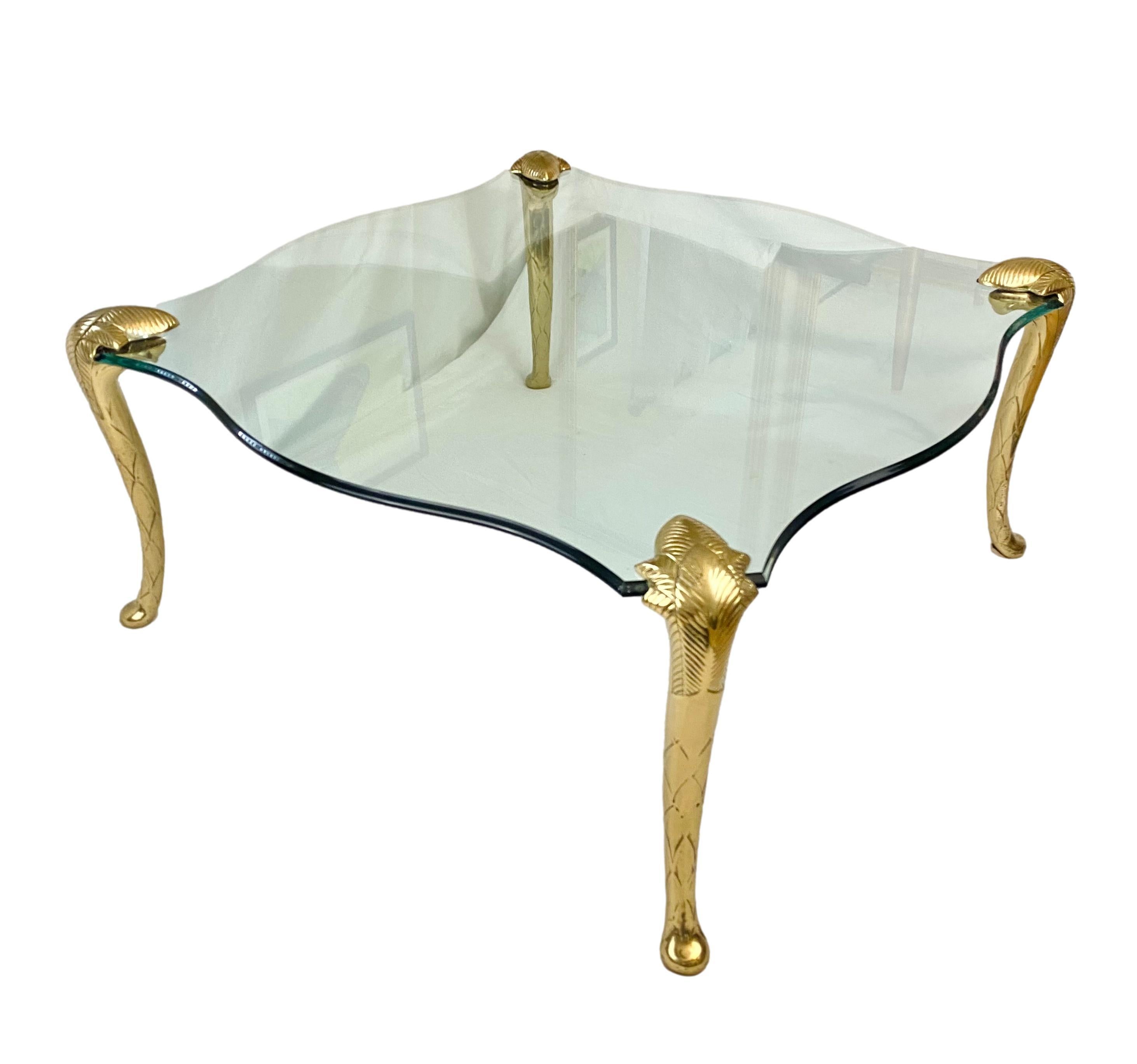 A vintage Hollywood Regency brass and glass coffee table in the style of Maison Jansen & P.E. Guerin. It features a beveled serpentine edge 