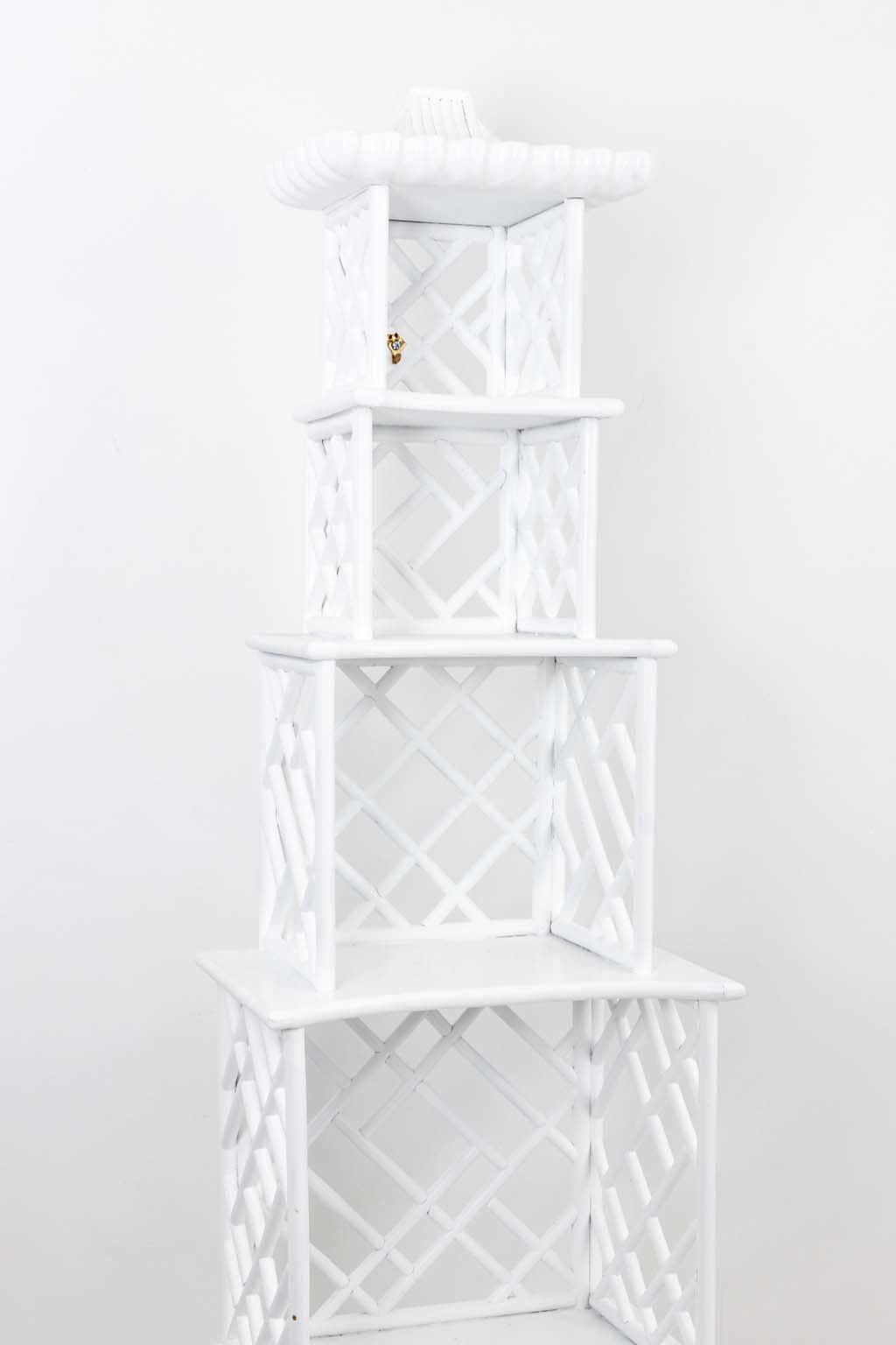 White painted Hollywood Regency style etagere in a pagoda form with 
enclosed lower two door cabinet and four graduated upper shelves. The 
piece also features open Chippendale fretwork construction and crowned 
with a carved pagoda roof
