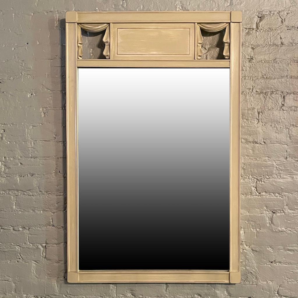 Lovely, Hollywood Regency, wall mirror features a painted wood frame with curtain motif. 