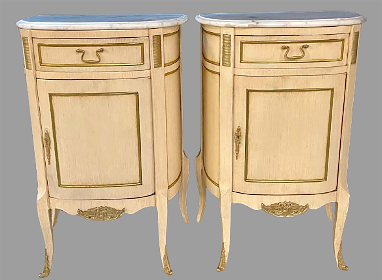 Demilune pair of Hollywood Regency painted end tables, nightstands or pedestals. Each having a d shaped form with a white marble top supported by a linen faux painted case of demilune form with a center drawer over one door leading to a shelved