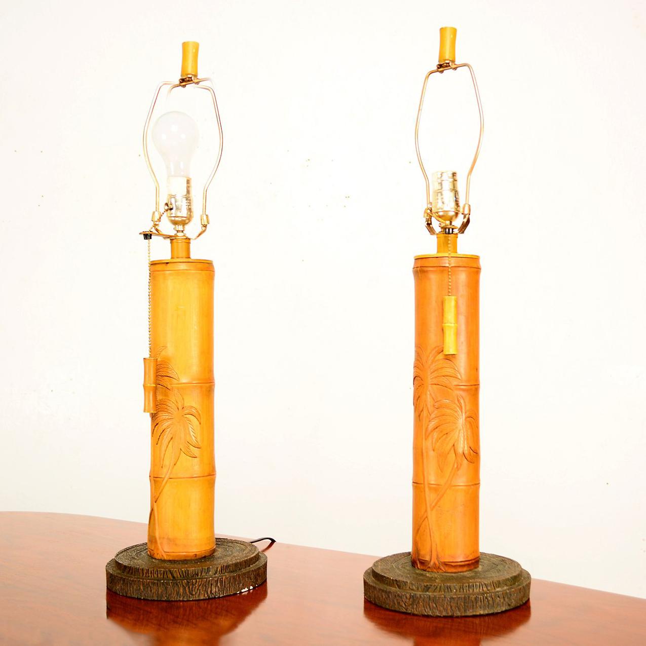 For your consideration a pair of bamboo table lamps.

Unmarked no information on the maker, 

Pull down chain and finial have the bamboo details.
The body is made of wood with a carved palm tree and the shape of the bamboo, mounted in a ceramic