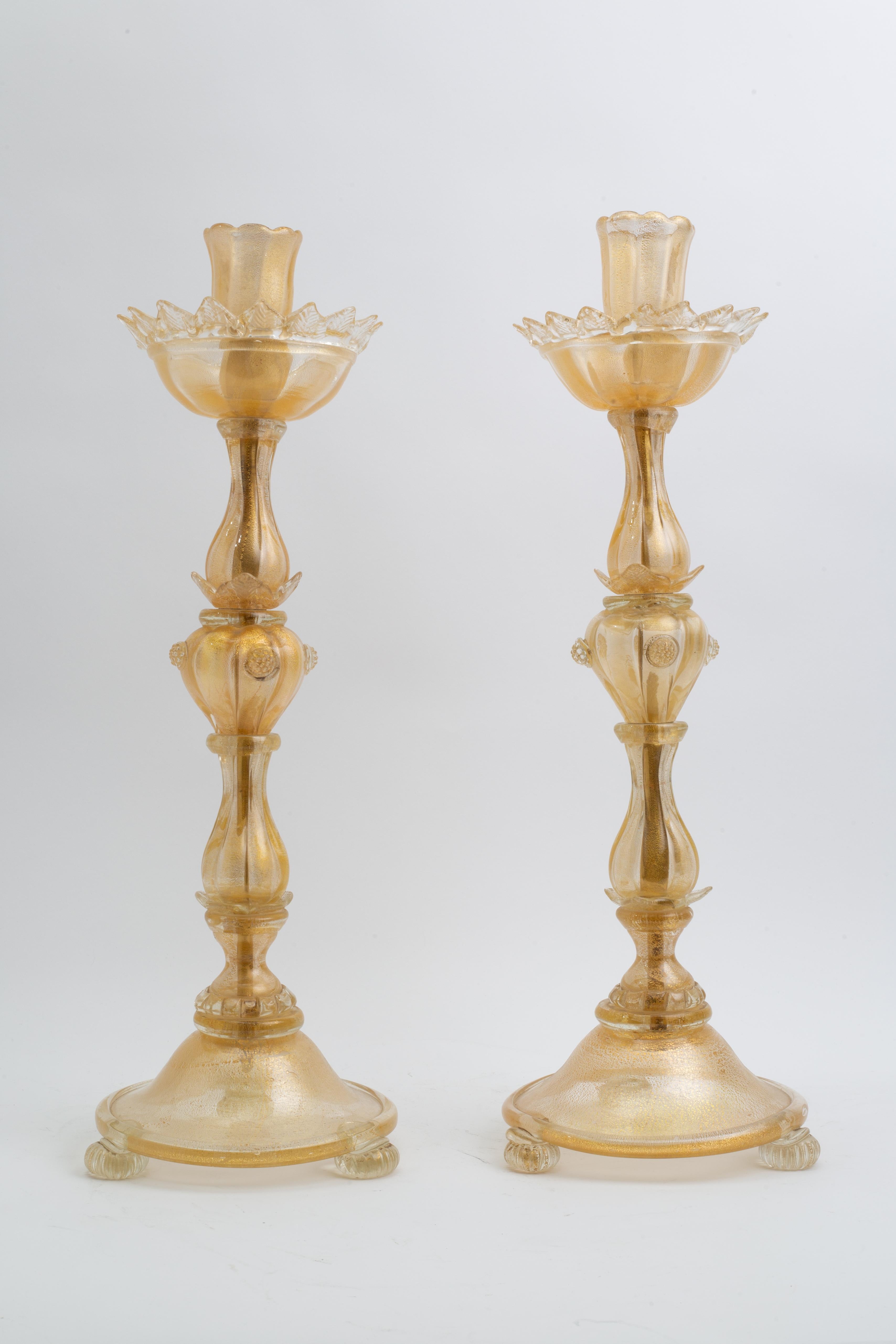 An Unusual Pair of Italian Murano Gold Speckled Flower Form Candlesticks

Each candlestick is composed entirely of hand-blown Murano glass with a rich infusion of gold inclusions, creating a translucent amber tone throughout the surface. The form