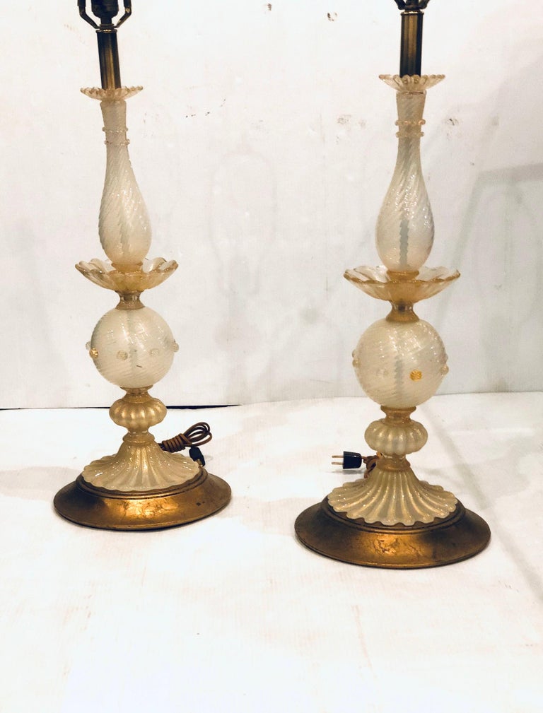 A beautiful pair of Italian Murano glass lamps, circa 1950s with original wood gold leaf bases, in great condition freshly rewired with a cloth cord, in great condition. The lamps are sold without lampshades, and are 29