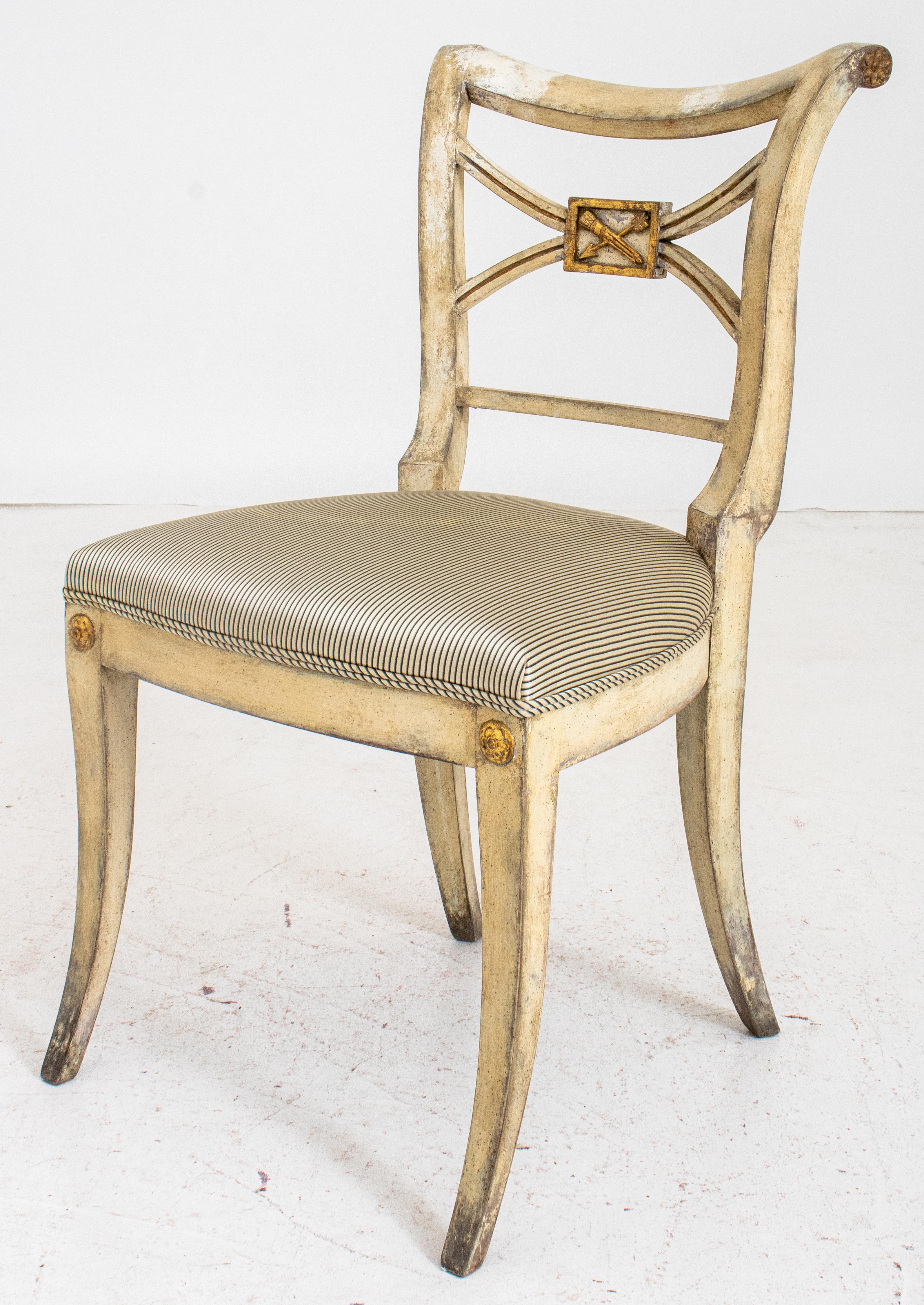 Hollywood Regency parcel gilt and gessoed side chair, in the manner of Syrie Maugham, with scrolling shaped crest rail above a shaped x-stretcher centering a gilded trophy depicting an arrow and quiver, above a shaped rectangular silk ticking