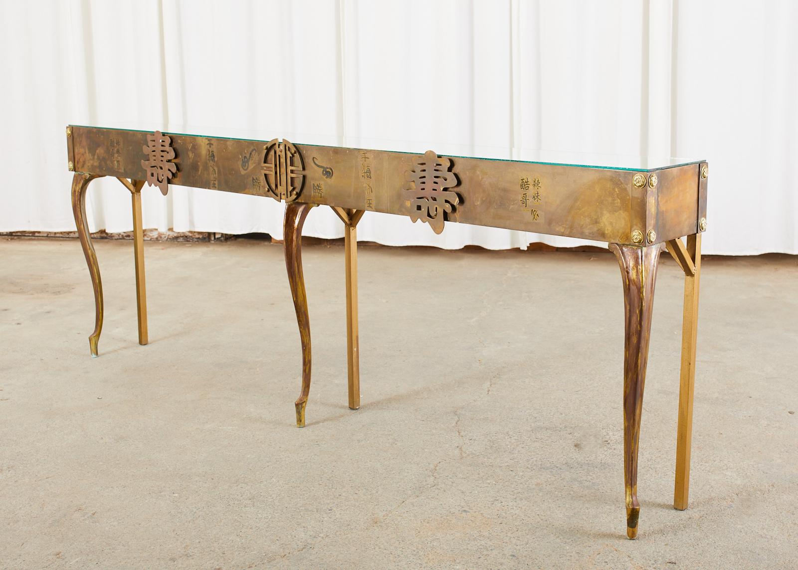 Fantastic long Hollywood Regency period console or sofa table featuring Chinese symbols and Asian motifs. Crafted in the manner and style of Bernhard Rohn for Mastercraft. The iron frame is covered with patinated brass affixed with shiny round brass