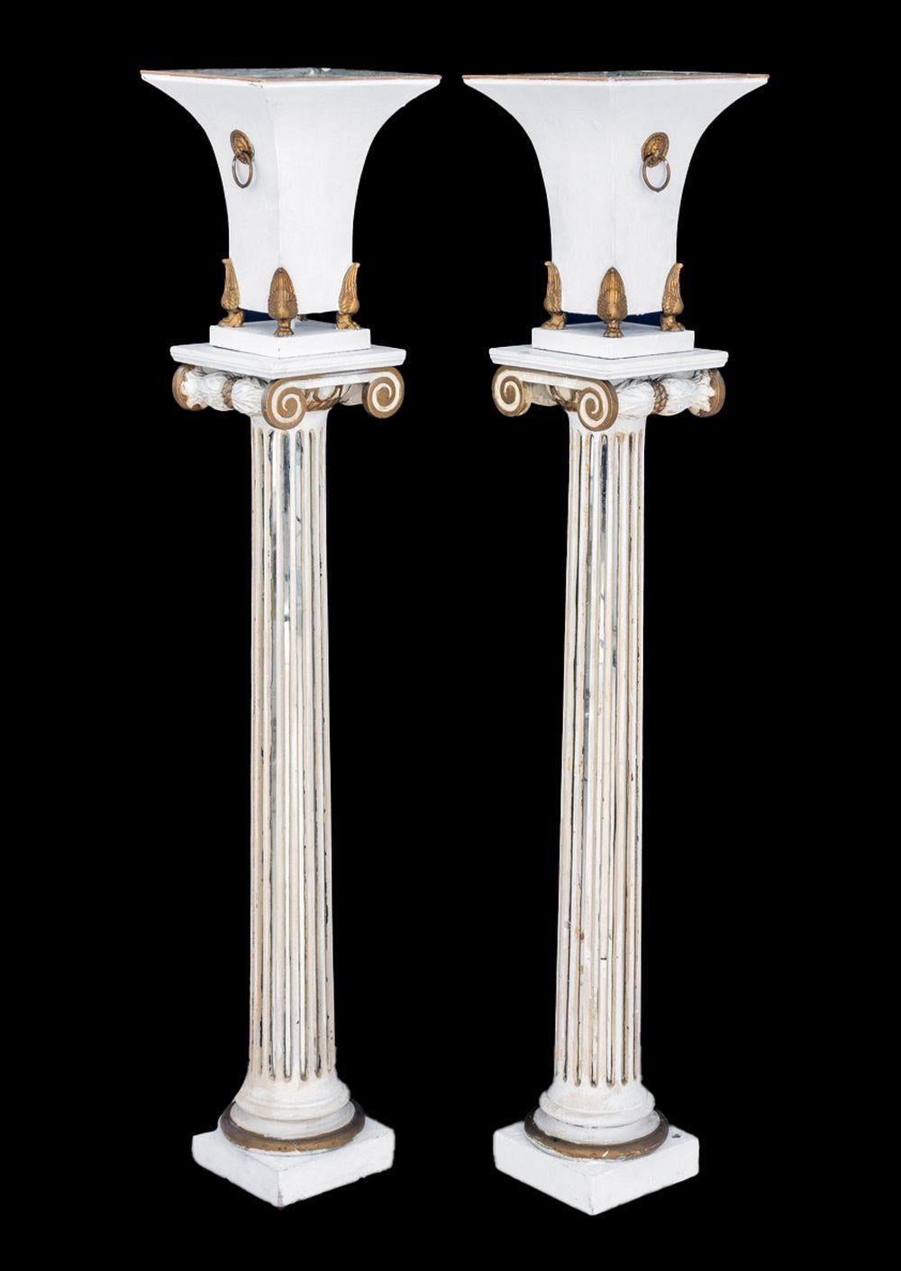 Coppia di torciere Hollywood Regency in metallo patinato, con maniglie ad anello a testa di leone su piedi a zampa in ottone montati su colonne ioniche scanalate a specchio che terminano in basi quadrate. 51