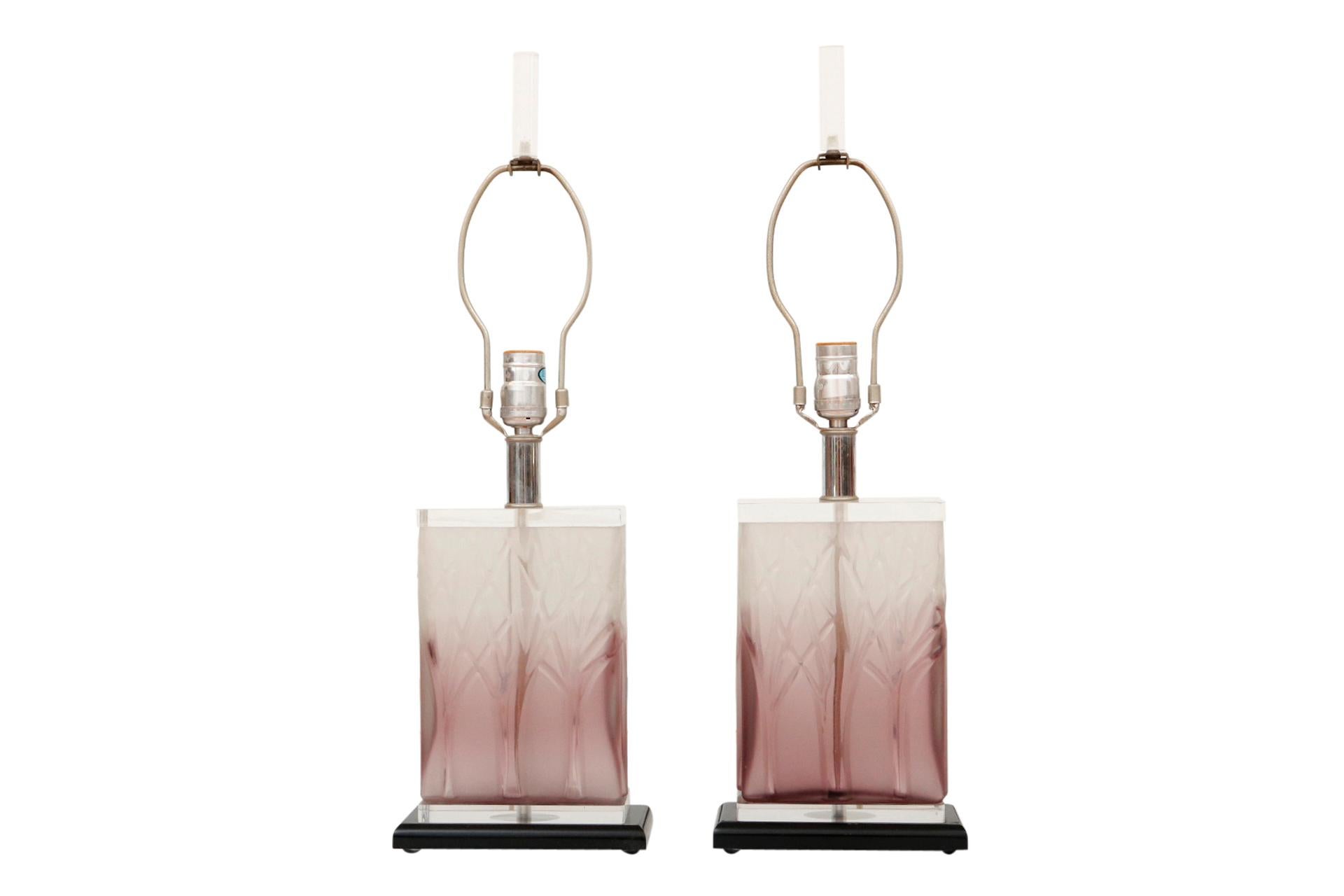 Une paire de lampes de table en lucite de style Hollywood Regency des années 1980. Les blocs de lucite translucide sont d'un violet riche passant au blanc et pressé avec des arbres à l'avant et à l'arrière. De courtes colonnes chromées supportent