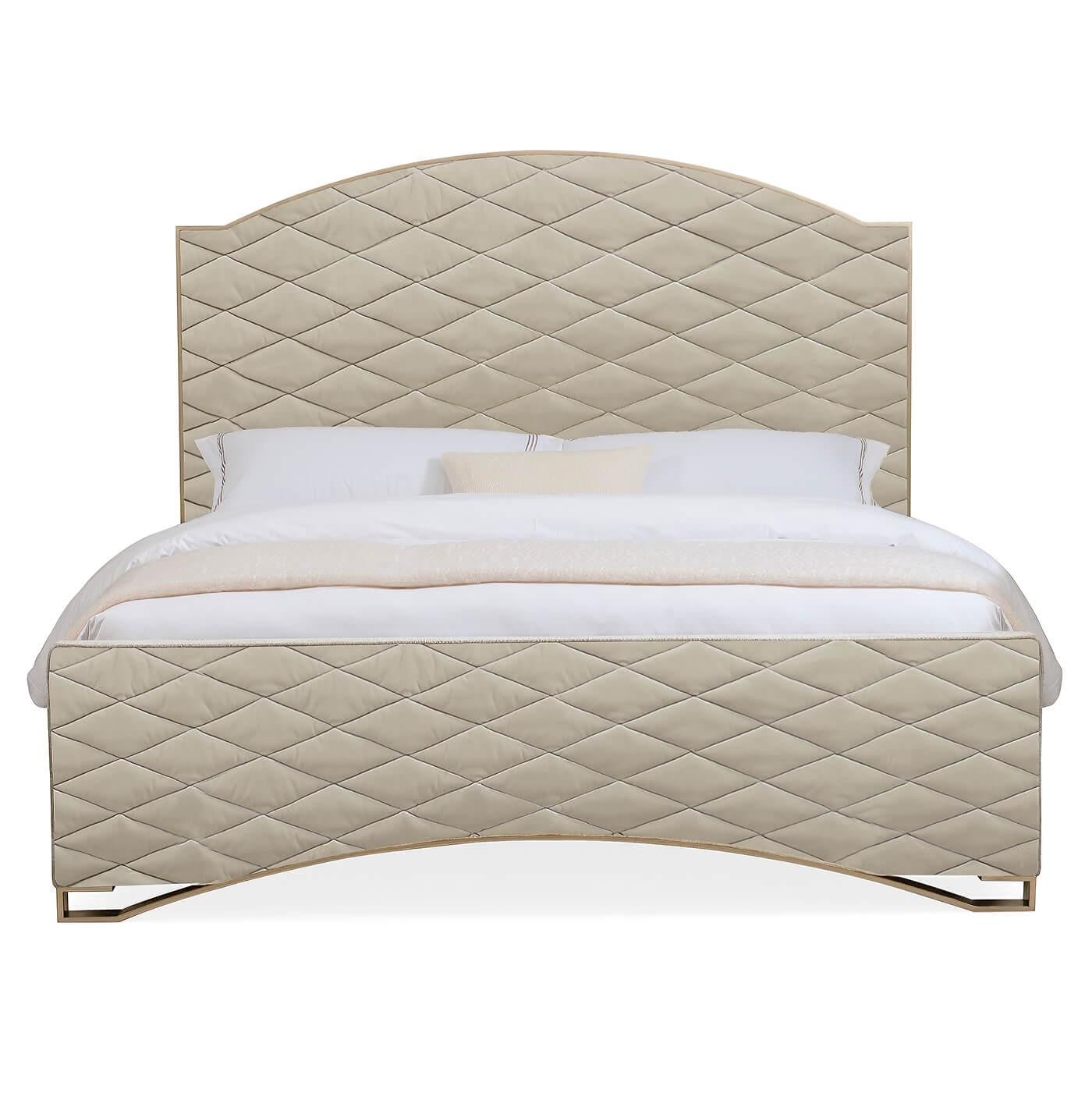 A Hollywood Regency style King size bed. This dramatic design features a quilted upholstered headboard and footboard. The tall, softly rounded headboard is trimmed in wood and finished with a golden shimmer painted finish while the bottom of the