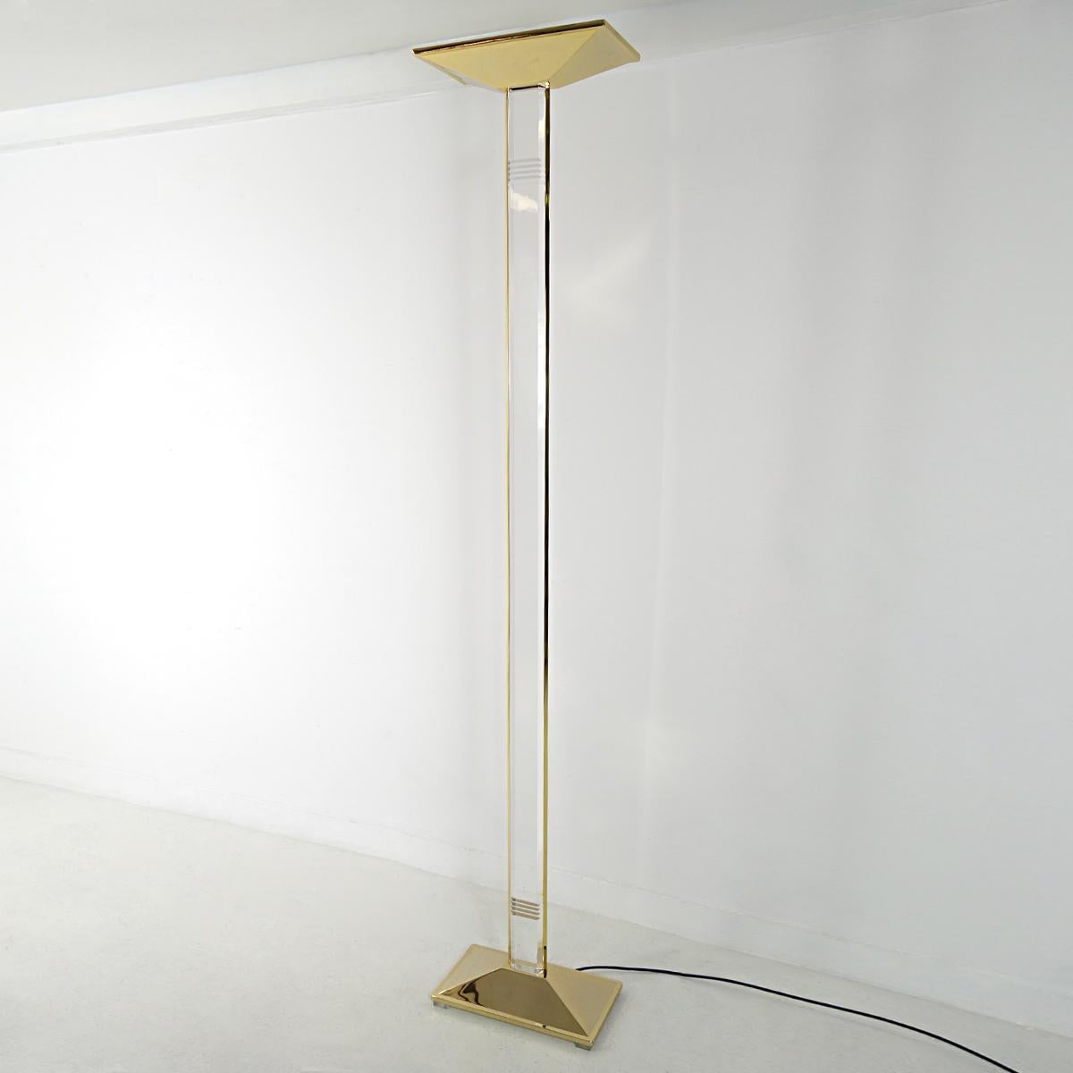 This elegant and classy floor lamp is made of brass and plexiglass. The shade, foot and sides of the pole are made of brass whereas the pole itself and the small stands the foot sits on are subtly made of Lucite. Lovely detail are the small 