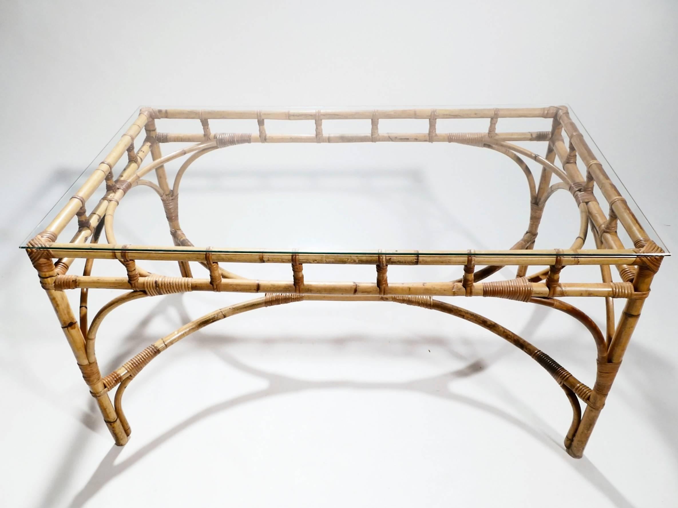 This rattan and bamboo table, with its crisscross-backed chairs and transparent tabletop, effortlessly balances the extravagant Hollywood Regency style and clean-lined Mid-Century Modern style. The clear glass surface allows the warm bamboo legs to