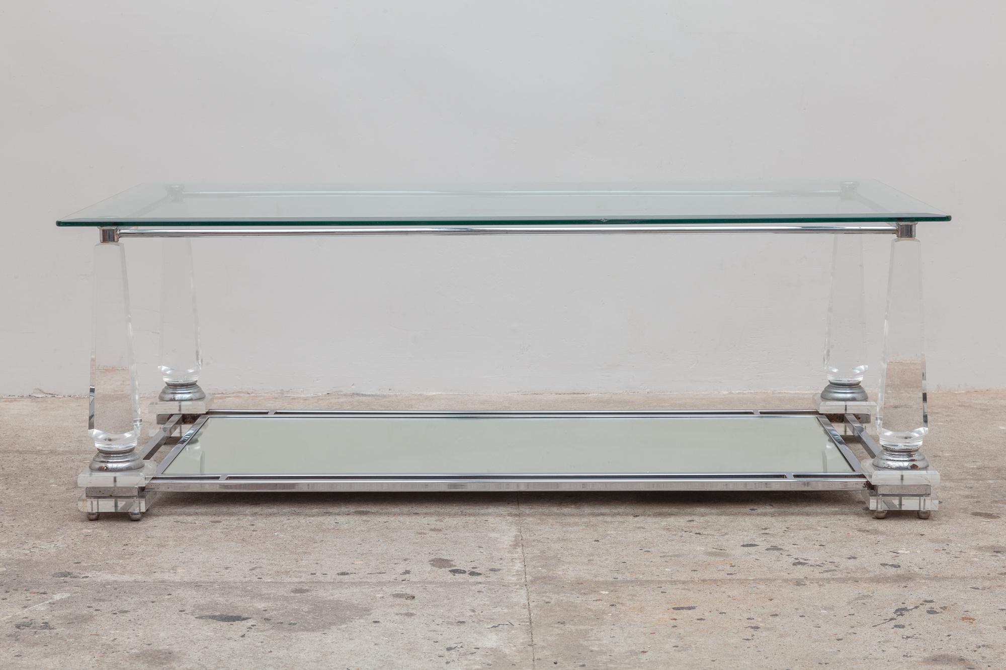 Vintage 1970s rectangular coffee table. Crystal Lucite obelisk legs support a lower mirrored shelf and a top shelf of clear beveled glass.Top of the table resting on the 4 obelisk legs which are magnificent well stabile and solid. Measurements: Dept