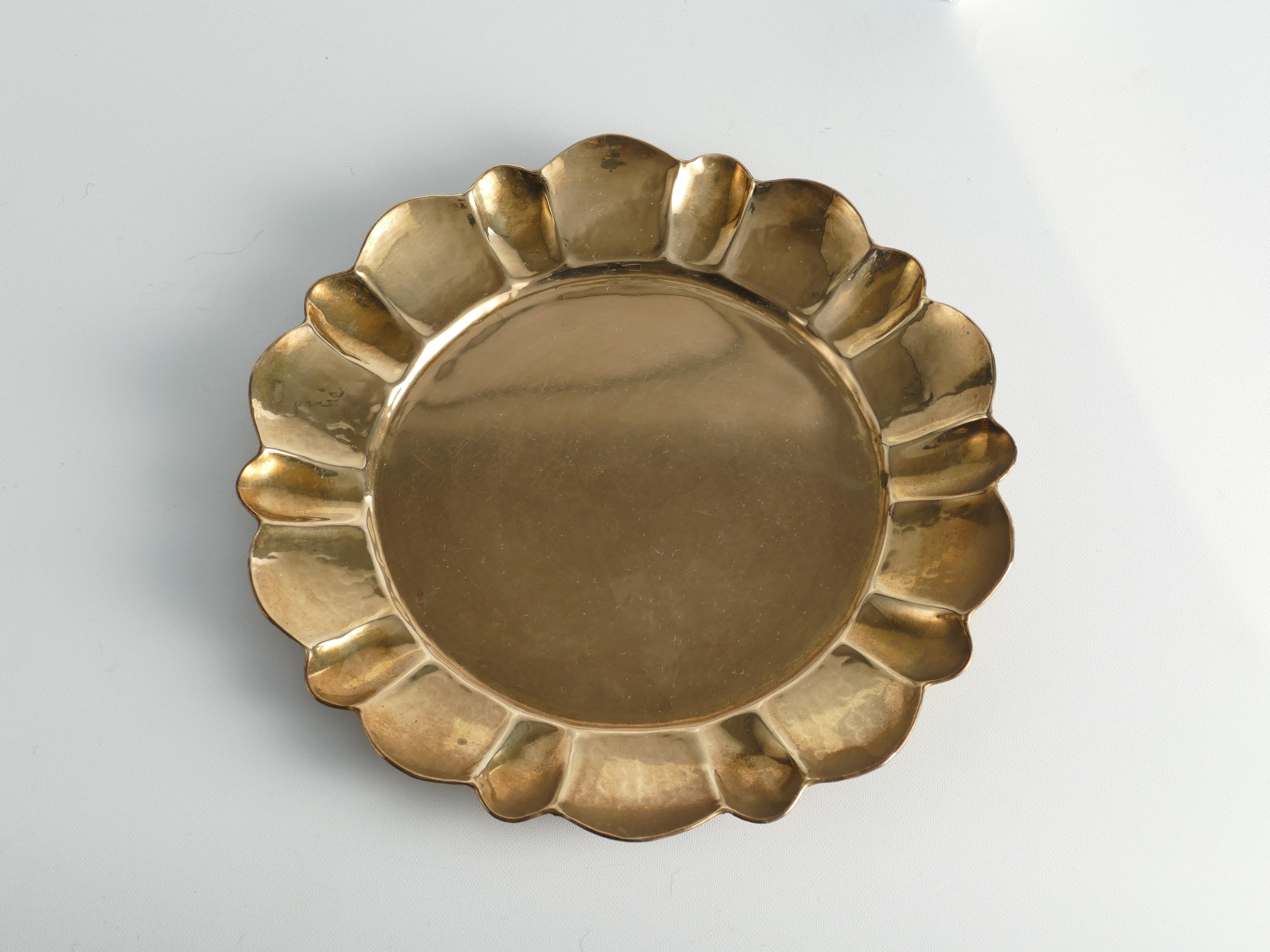 Masterfully crafted Hollywood Regency / Swedish Grace round brass tray by Firma Lars Holmström, Sweden. The tray has a round shape with a gracefully contoured, hand-hammered edge. Manual operation and stamped for authenticity. The hammered decor and