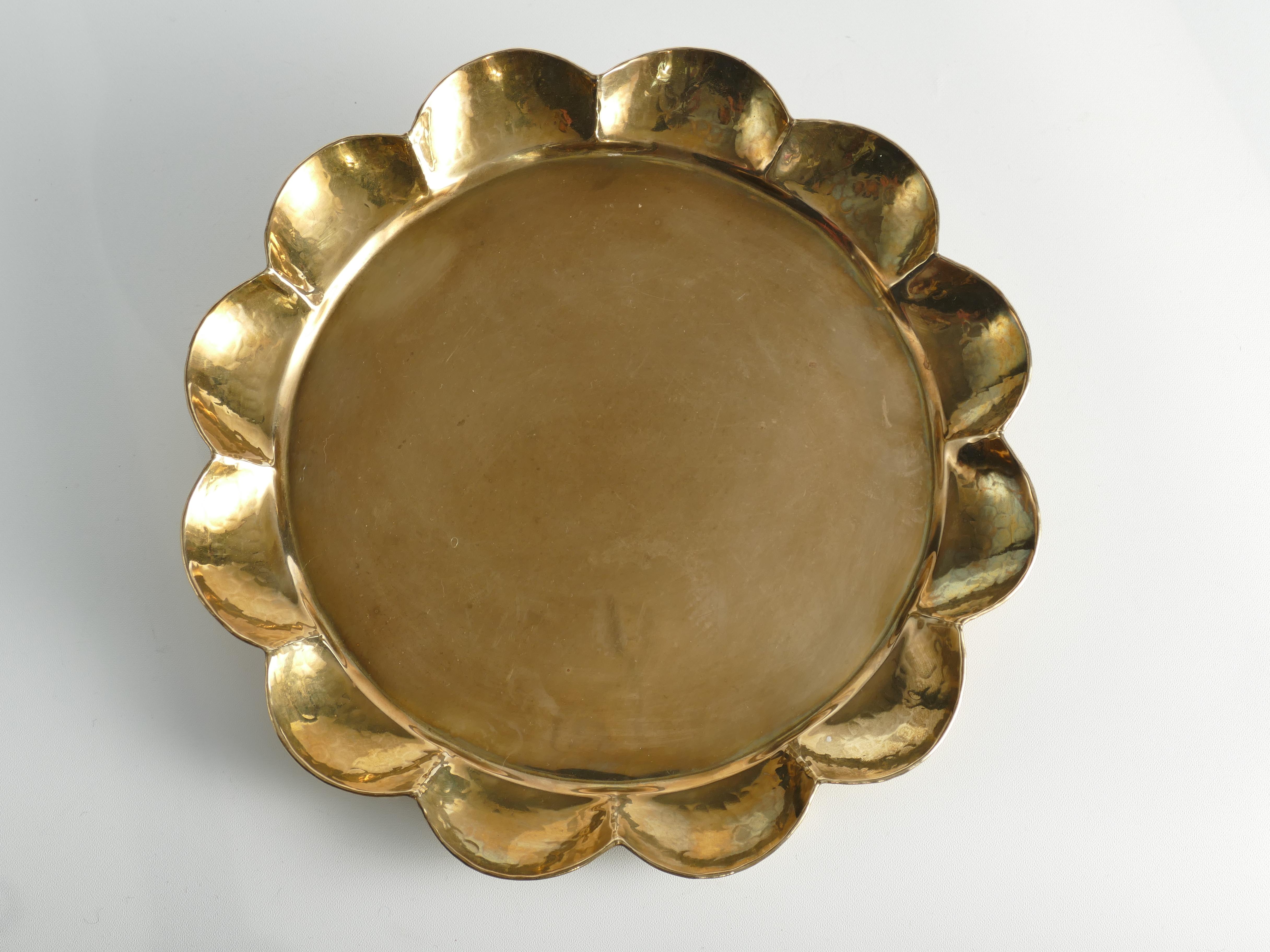 Masterfully crafted Hollywood Regency / Swedish grace round brass tray designed by Arvid Johansson (1862-1923), at Arvika Konstsmide, Sweden. The tray has a round shape with a gracefully contoured, hand-hammered edge. Manual operation and stamped