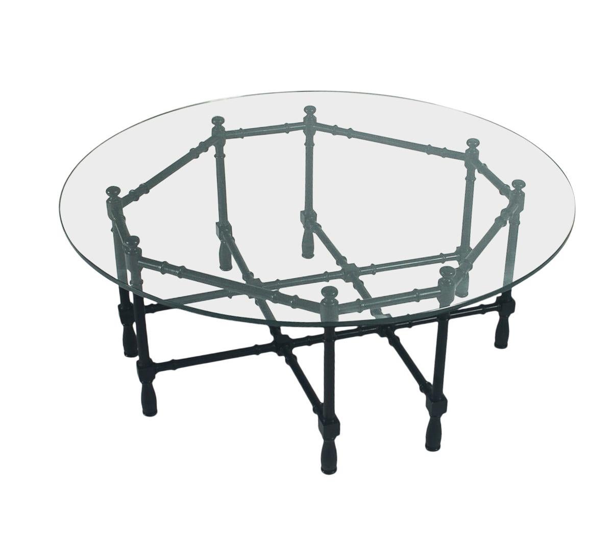 A circular glass coffee table circa 1970's. Its features a black lacquered faux bamboo base with thick glass circular top.