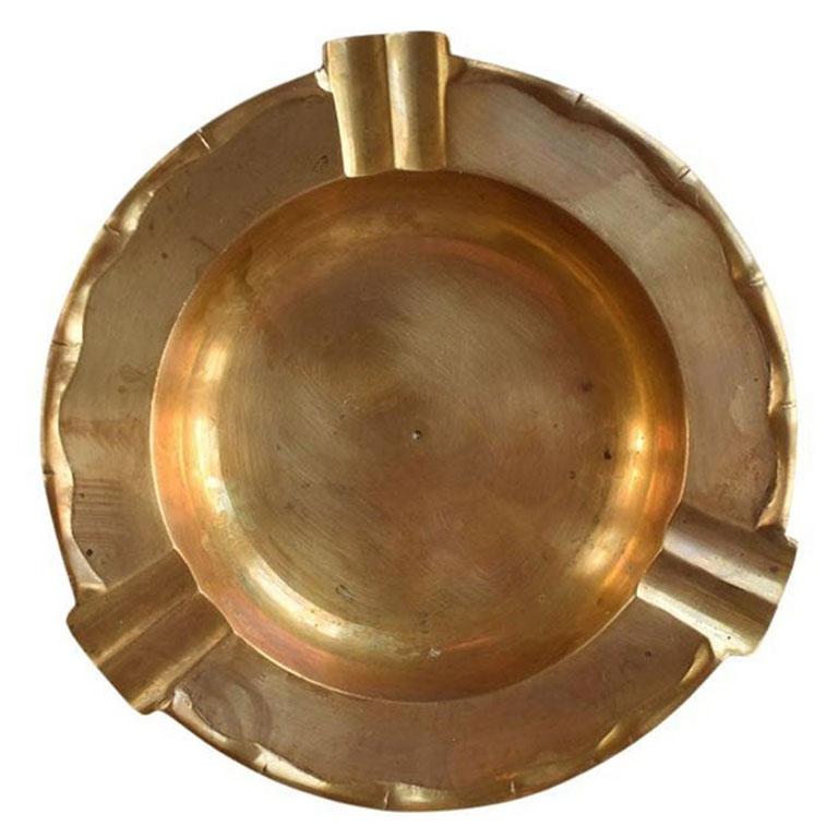 A shiny solid brass round faux bamboo Hollywood Regency ashtray. Use this dish as a trinket dish, ashtray, or catchall. Created from solid brass, this piece is quite heavy. The edges are rounded up and create more of a bowl than a plate. The edges