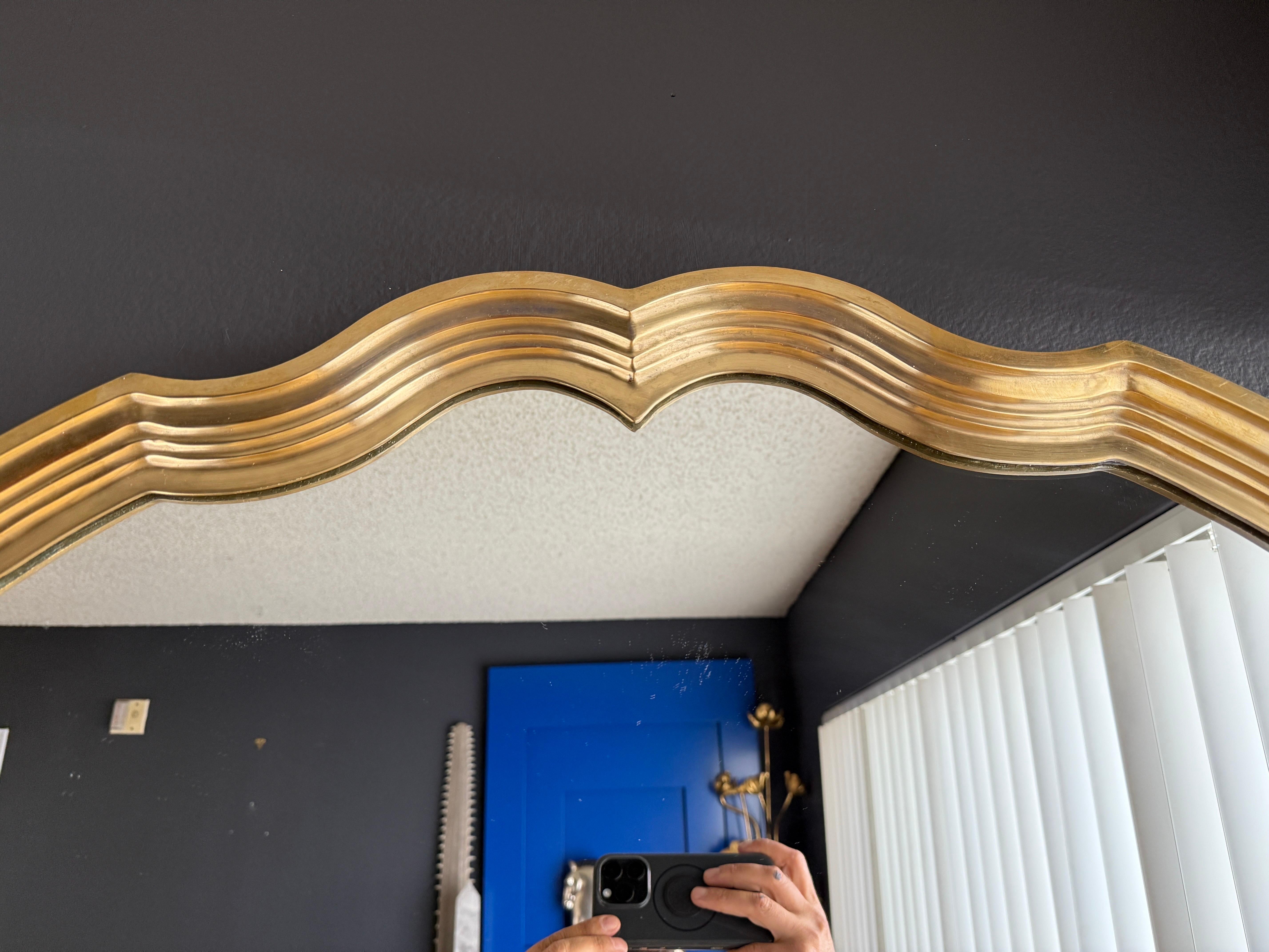 Hollywood Regency scalloped shape brass wall mirror.