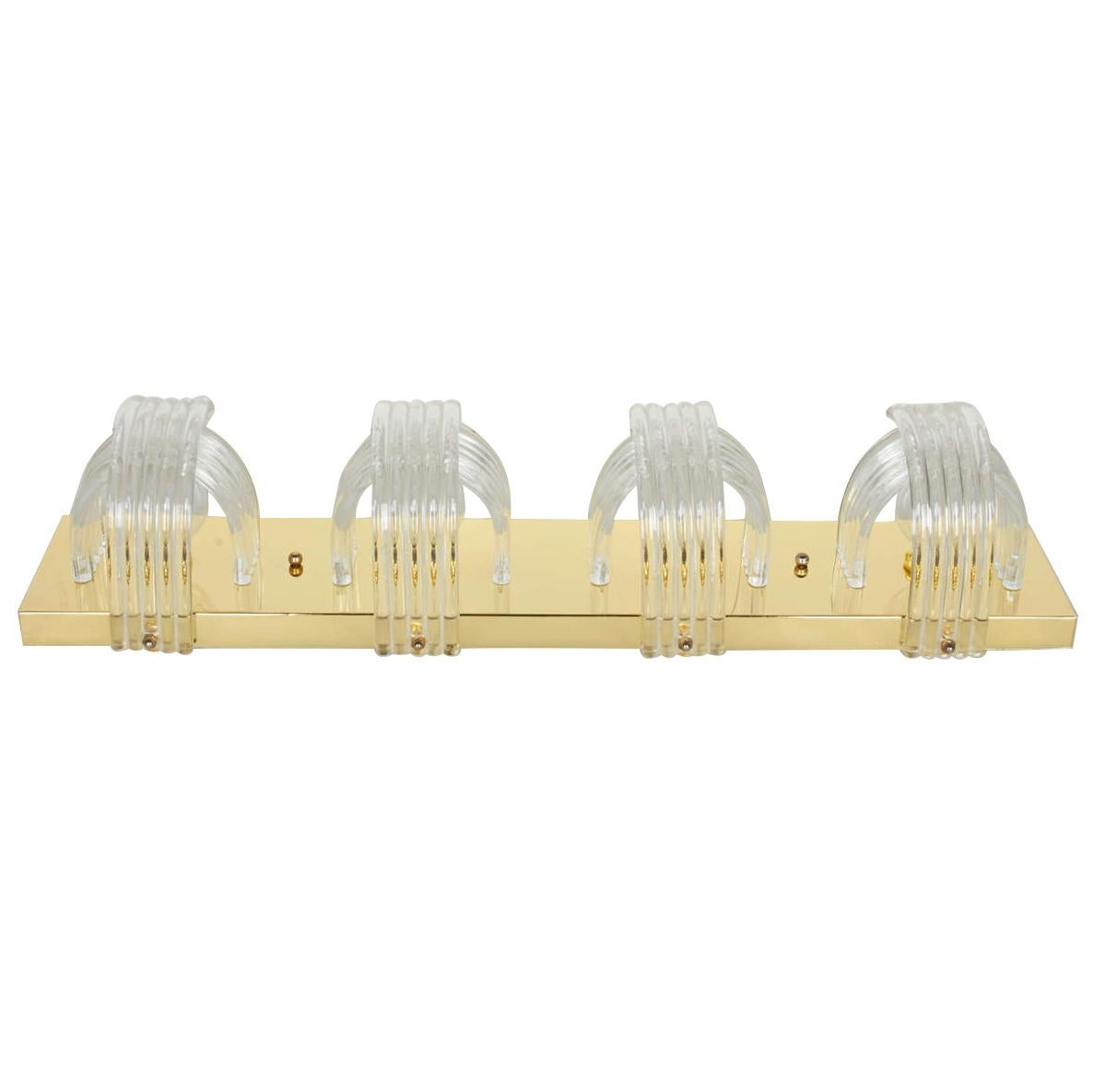 Mid-Century Modern Hollywood Regency wall sconce comprised of a polished brass frame, with shades made of sculpted Lucite rods. The four series of curved Lucite rings create beautiful prism lighting, while concealing the light bulbs. Perfect
