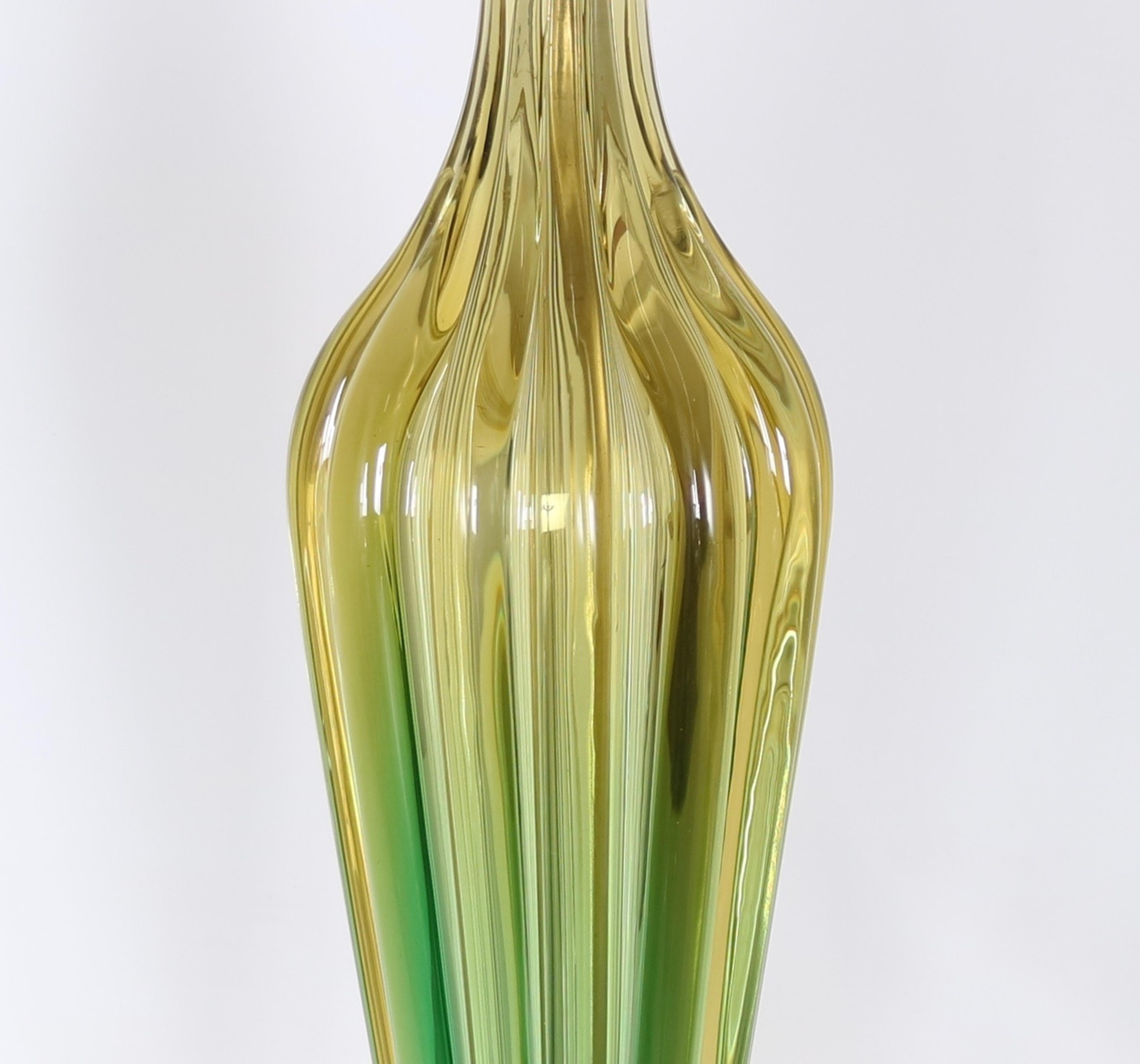 Seguso lamp crafted in murano glass in hues of green and gold. The piece features a ribbed amphora body in ombre gold to green. The lamp stands on a circular gilded wooden base. Fully restored with all new wiring and hardware including a double