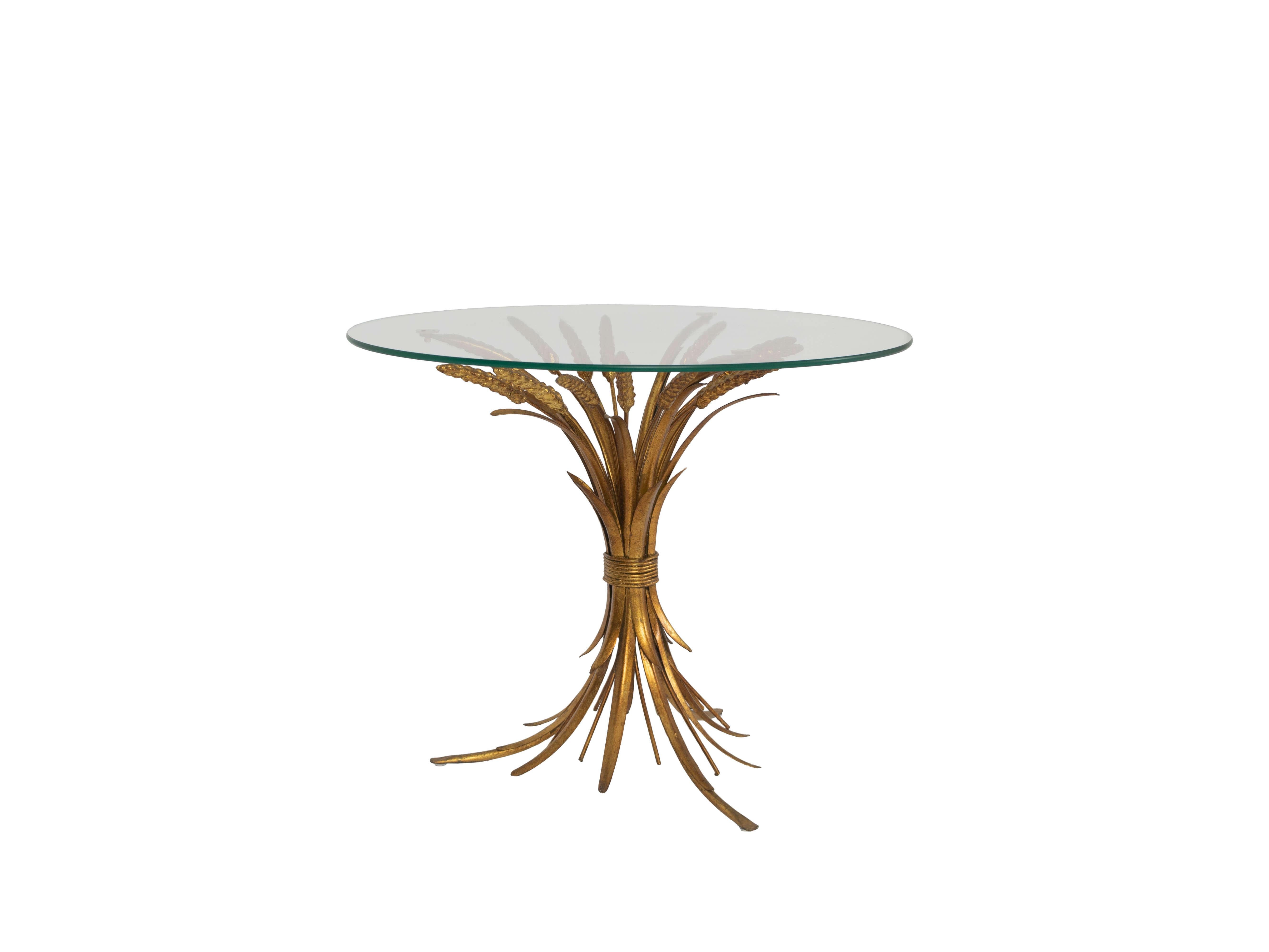 Nice Hollywood Regency, 'Sheaf of Wheat', coffee table from circa the 1950s. The table has a gold-colored, richly decorated, base in the shape of a sheaf of wheat. On top of three of the elements rests a round glass top. It is a great example of the