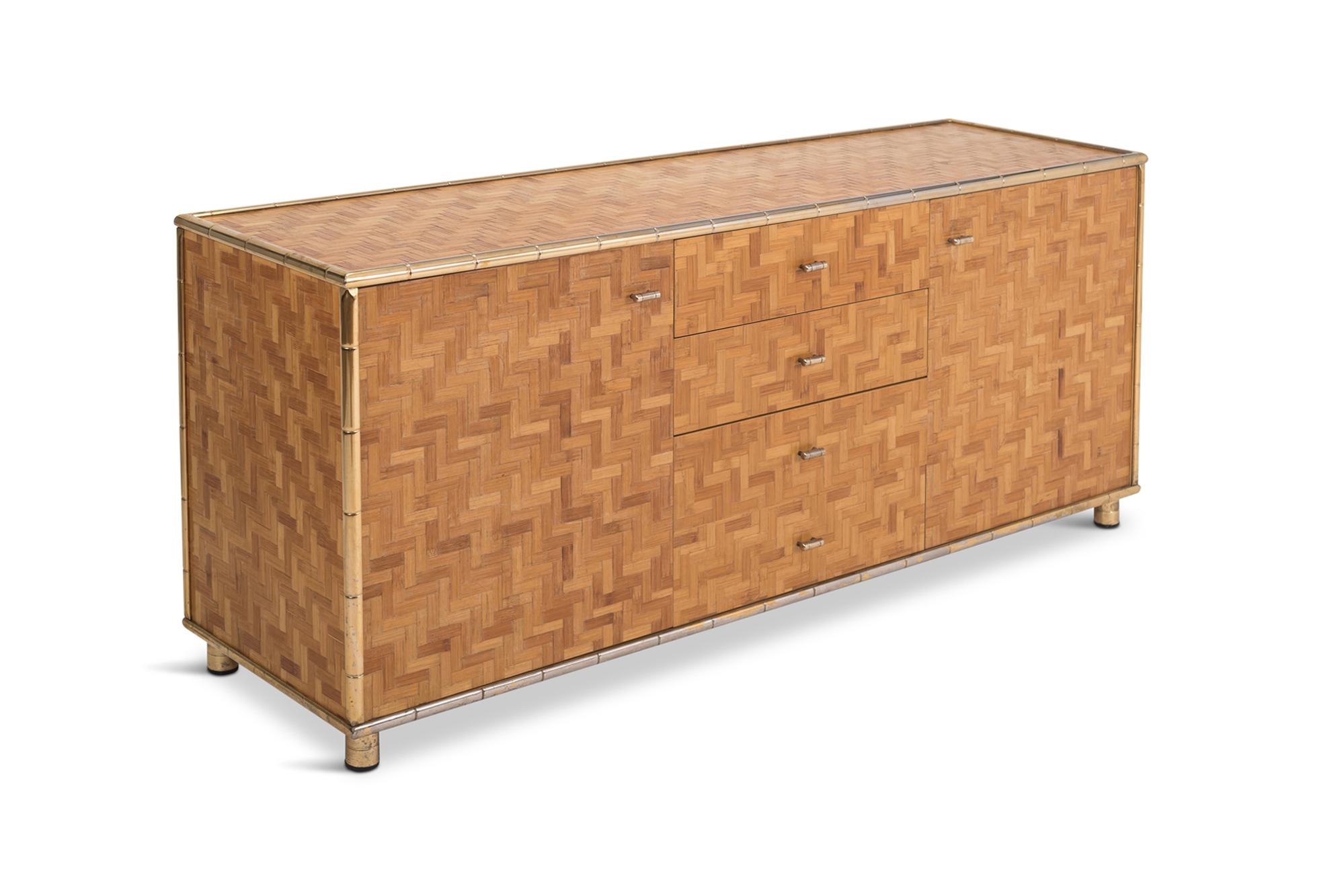 Rattan cladded sideboard with brass bamboo shaped edges, giving this item a very warm (almost tropical) appearance. 

In Hollywood Regency / Italian glam style, rests on four small brass legs, and provides plenty of storage space due to its large