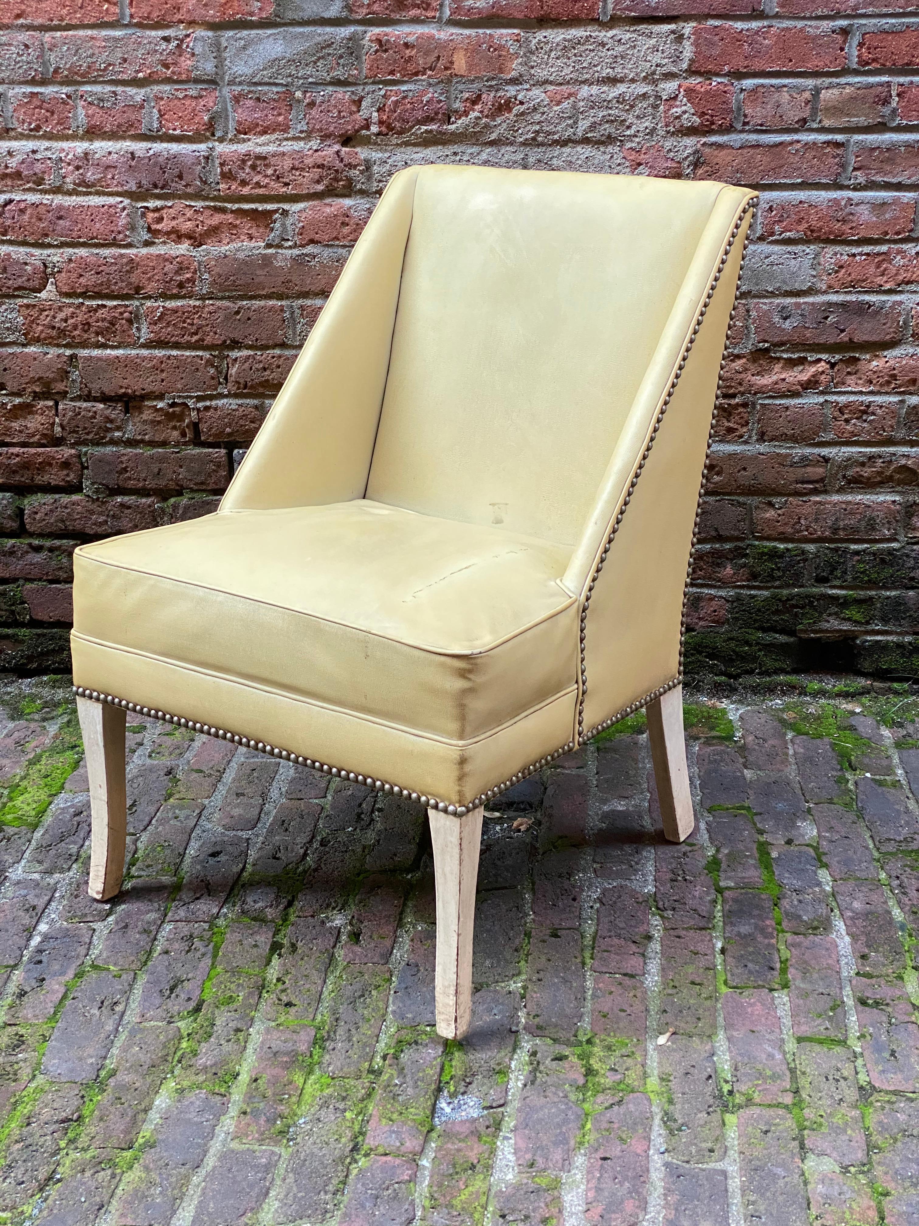 Elegant slipper chair, circa 1940-1950. Old off white vinyl upholstery with nice tacked edge detail. The frame is structurally sound and sturdy. Reupholstery is suggested, so you get to determine how beautiful one can make this chair. Overall wear,