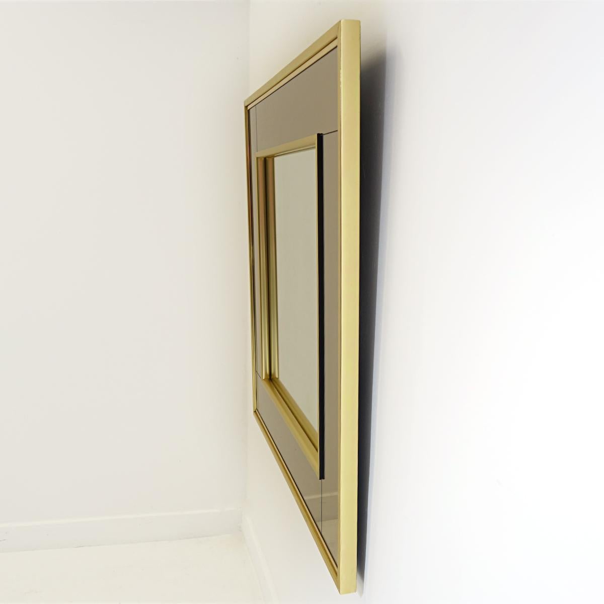 This square mirror has a center made of regular mirror glass which is framed by a champagne colored outside. All this framed in brass. A magical combination.