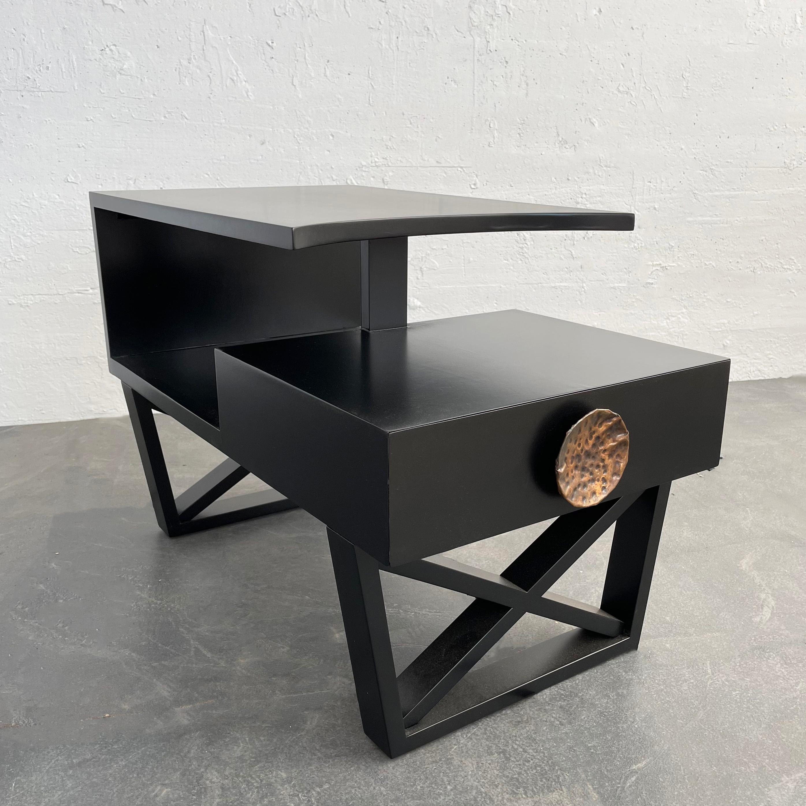 Glamourous, Hollywood regency, black lacquered mahogany, stepped side table attributed to James Mont features dramatic elements like a scooped edge top tier, framed X bases and oversized, brutalist, hammered copper pull on it's storage drawer. It's