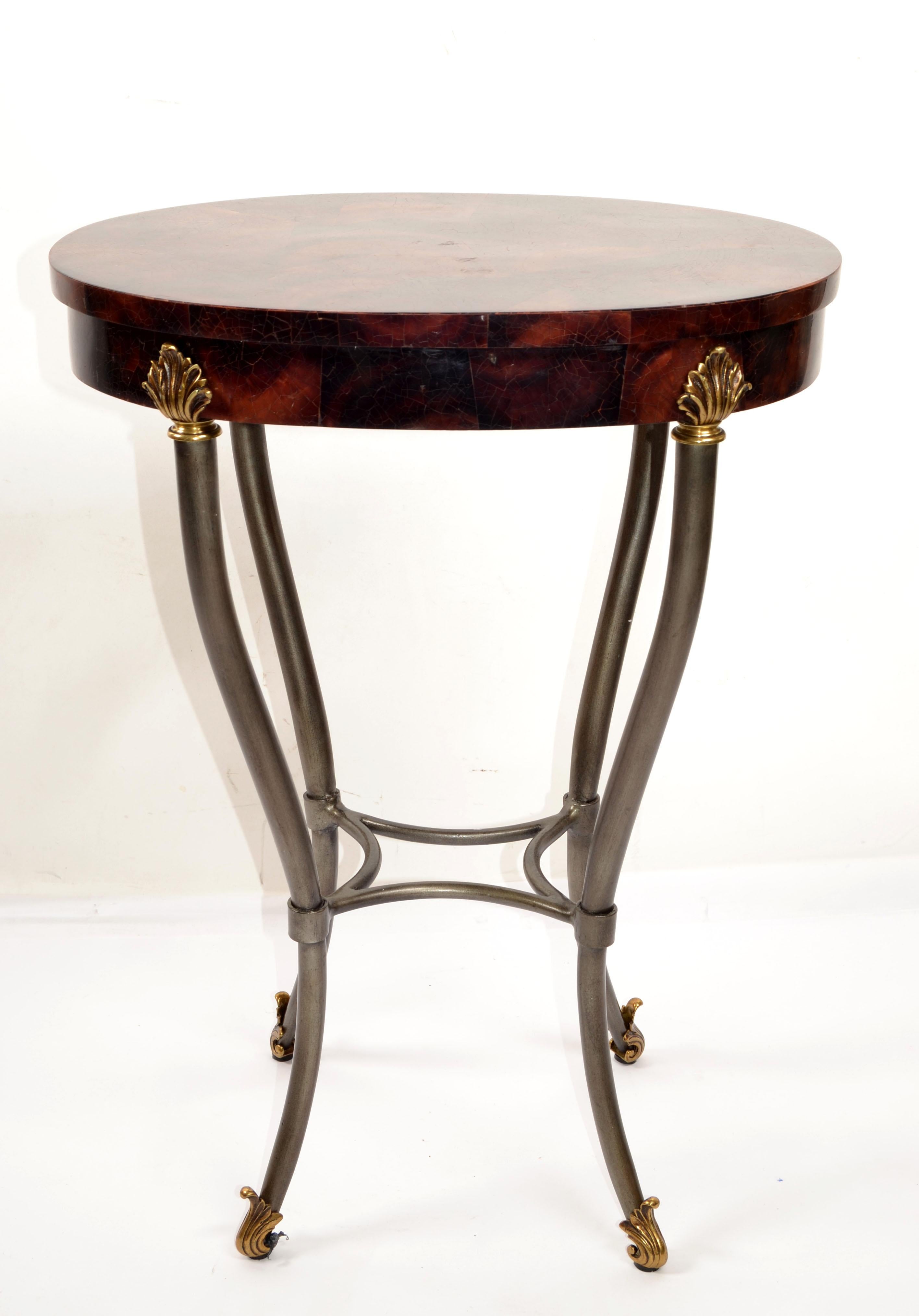 Table d'appoint ou d'appoint ovale en bois, en fausse corne tessellée, de style Hollywood Regency.
Base en fer forgé argenté foncé avec un plateau ovale en bois et en corne décoré de coquillages en laiton et de pieds en volute.
En bon état vintage
